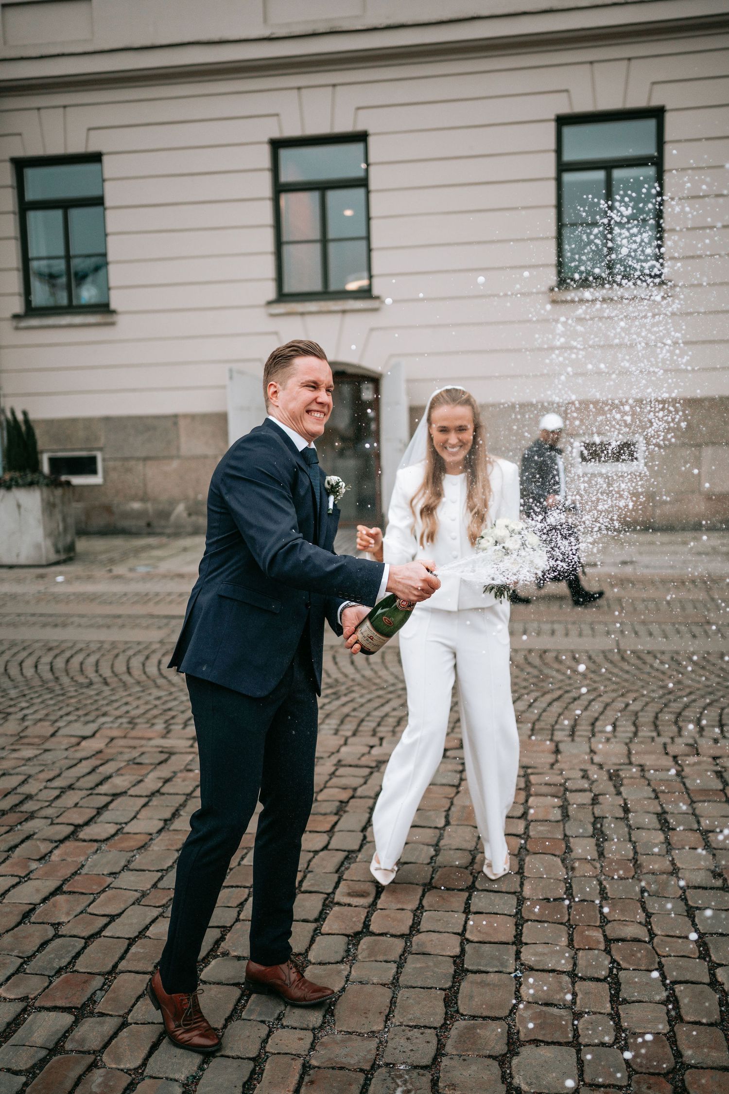 Brudpar firar utanför rådhuset i Göteborg efter vigseln med champange. Bröllopsfotografering borglig vigsel.