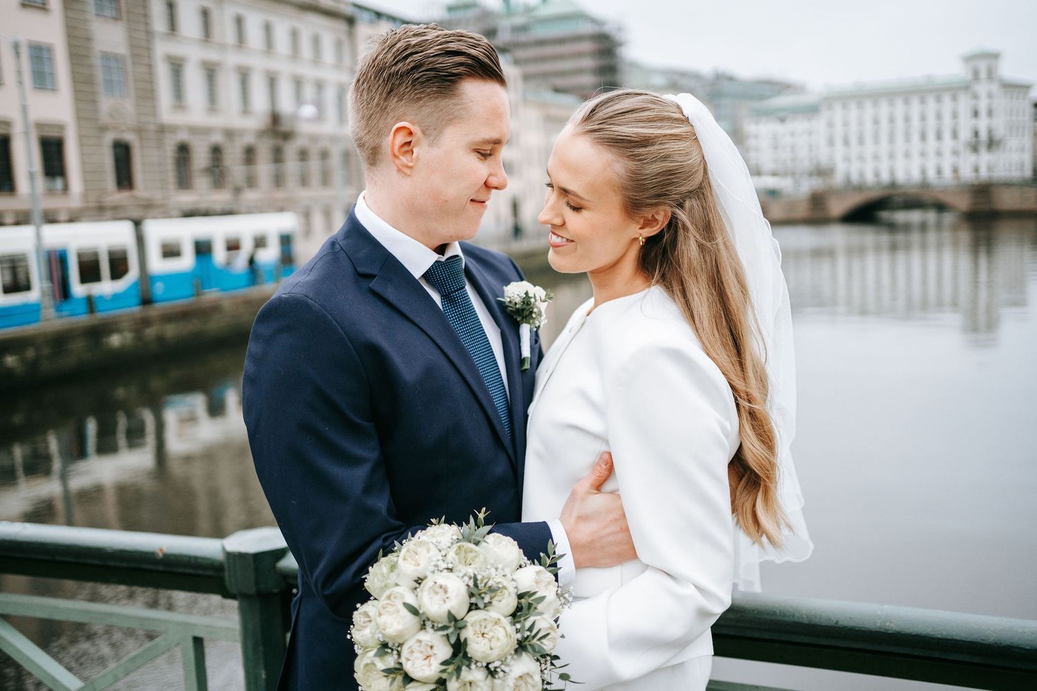 Brudpar delar ett romantiskt ögonblick på bro nära rådhuset i Göteborg med kanalen i bakgrunden, bröllopsfotograf göteborg