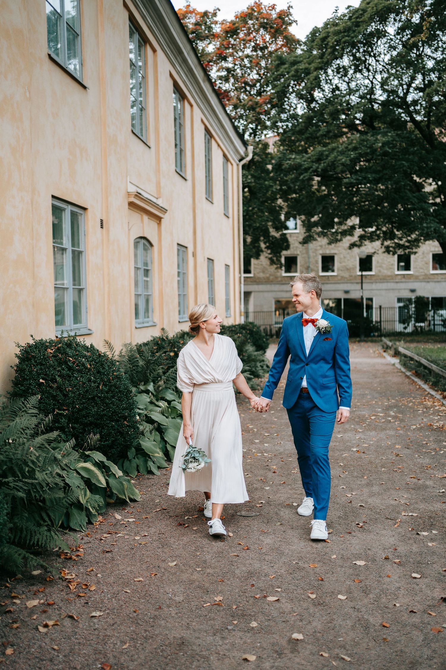Brud och brudgum går och håller varandra i händerna vid kronhusbodarna i göteborg innan borglig rådhusvigsel, gifta sig i rådhuset fotograf