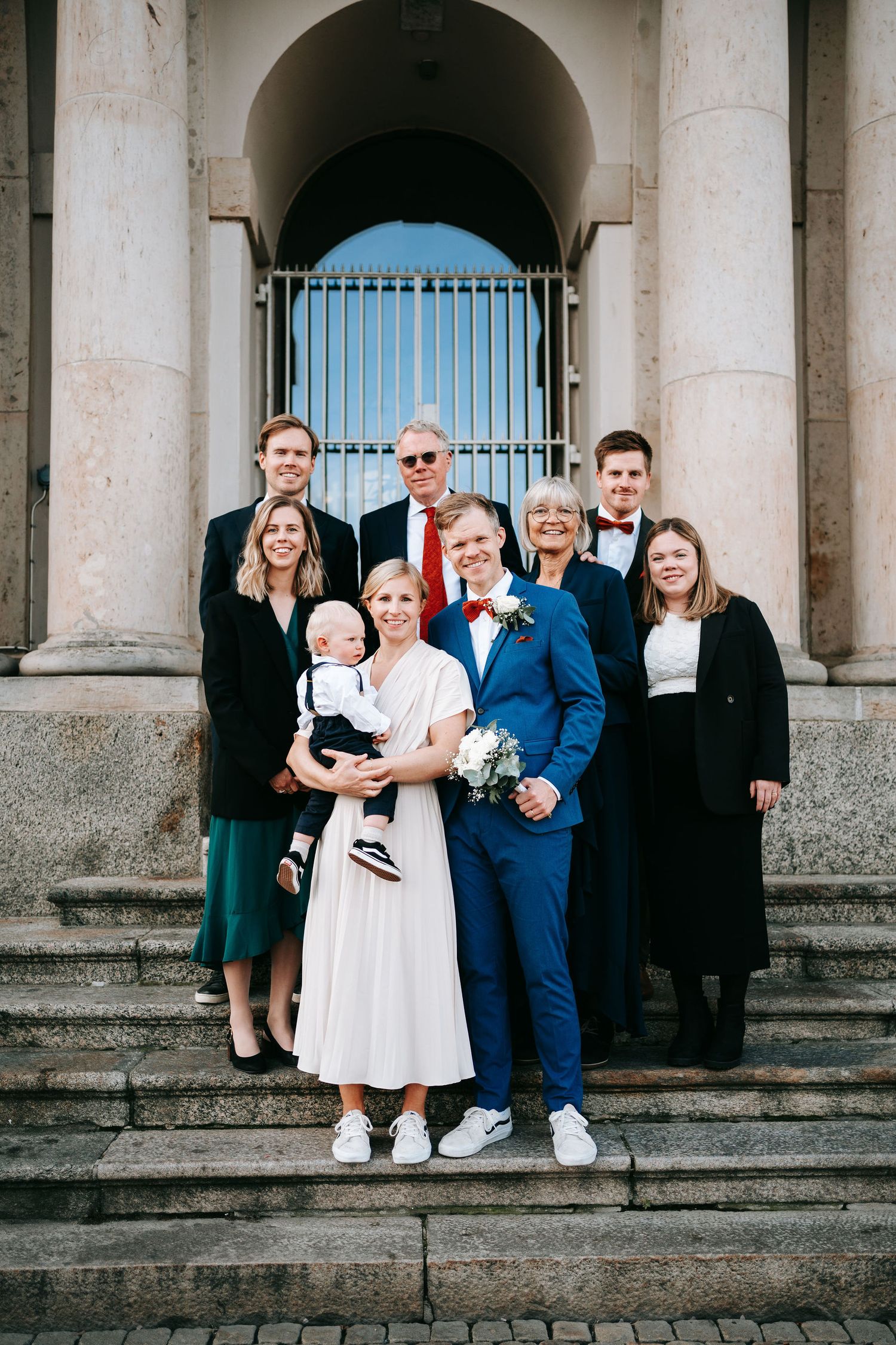 Gäster tillsammans med brudparet utanför rådhuset på trappan för gruppporträtt, bröllopsfotografering