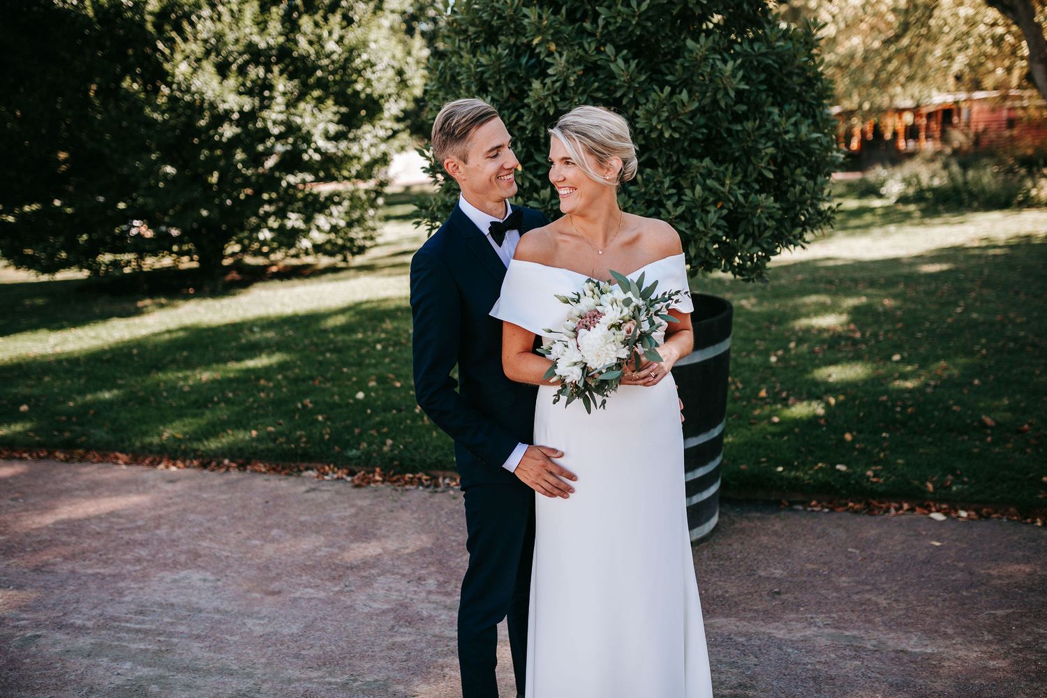 brudpar som omfamnar varandra och skrattar i trådgårdsföreningen i göteborg innan vigsel i rådhuset i september, bröllopsfotografering