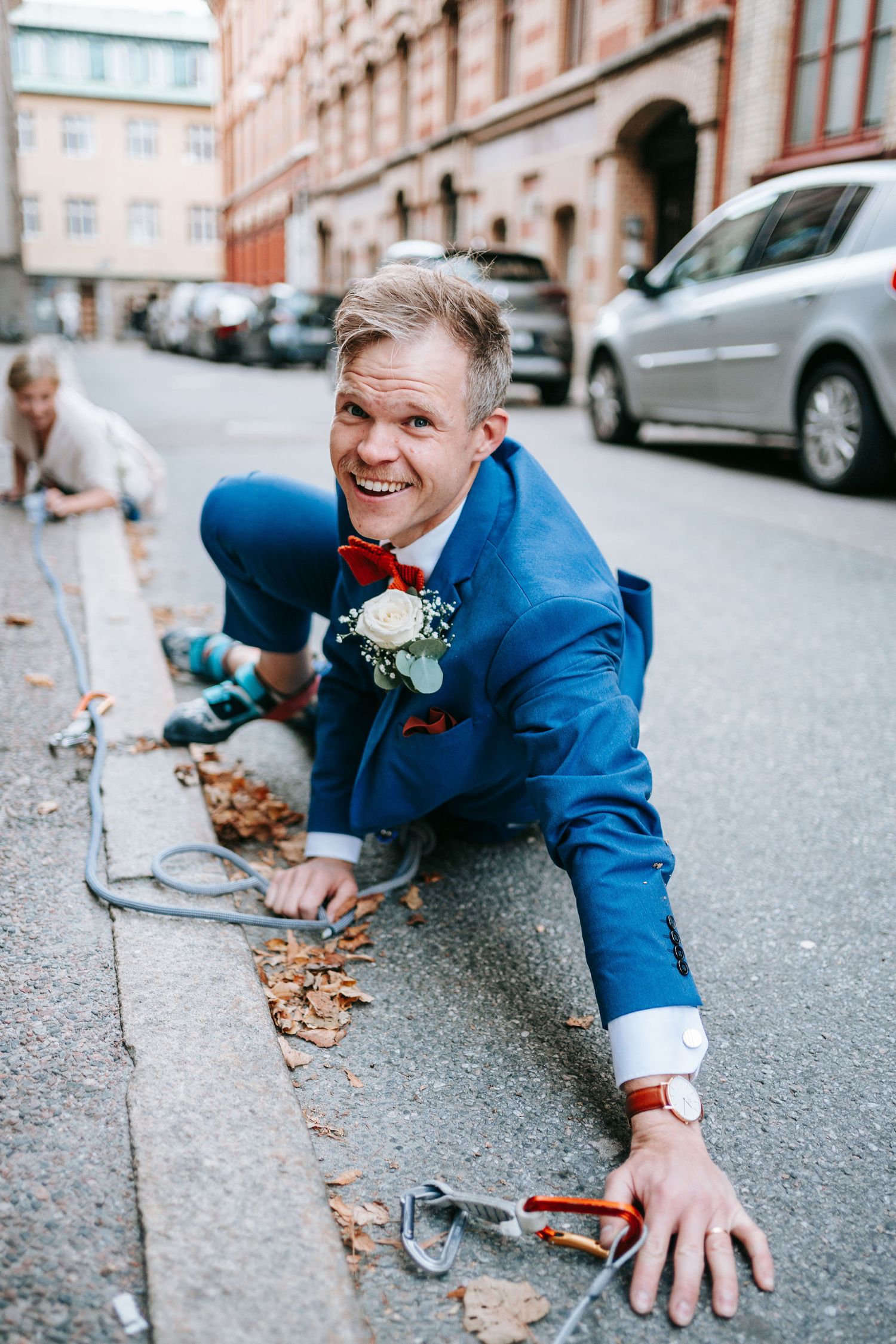 Brud och brudgum ligger tillsammans på gata i Göteborg med klätterrep under lekfull fotografering, bröllopsfotografering