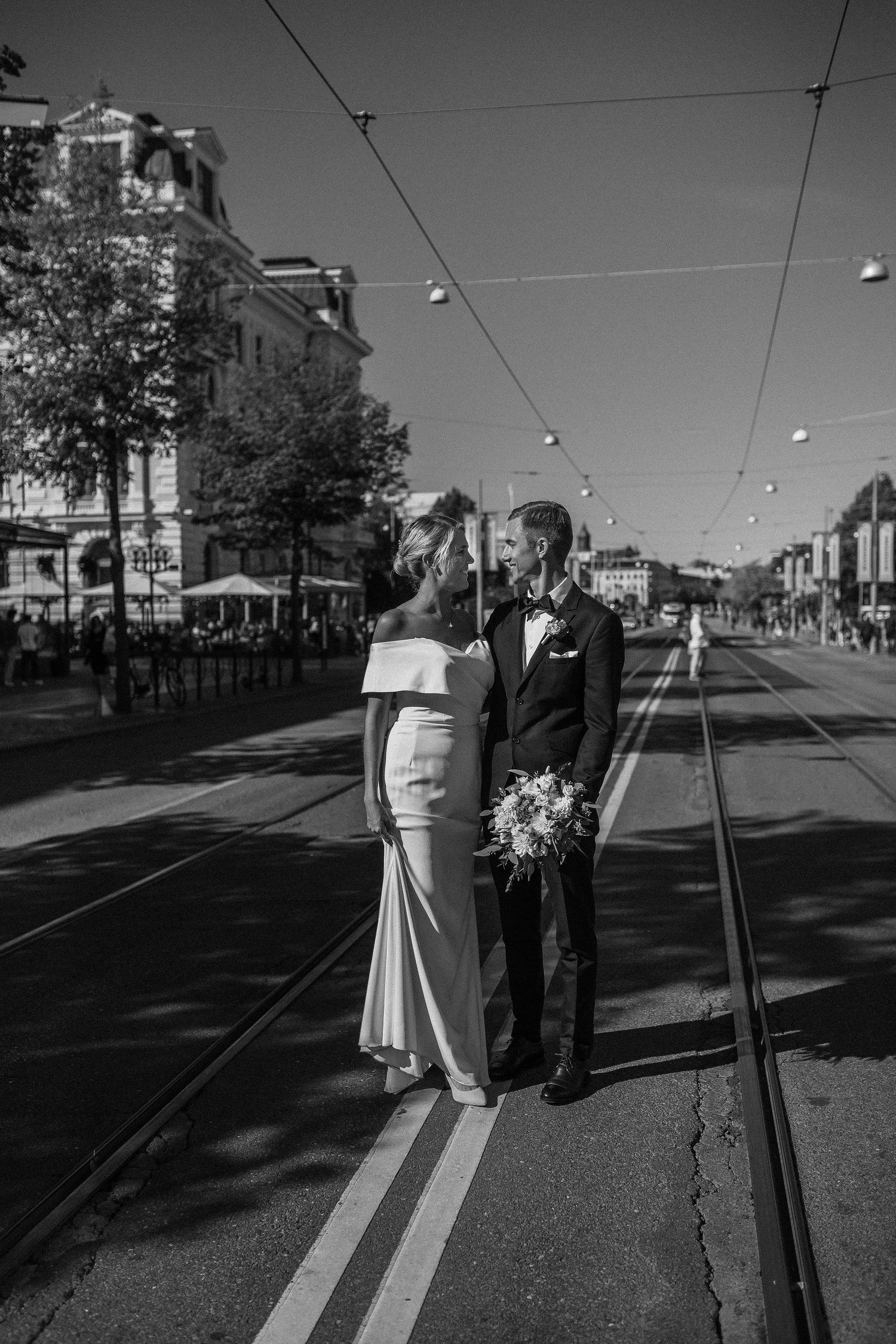 svartvit dokumentär bild på brudpar som går längst med spårvagnsspåren på avenyn, borglig vigsel i göteborgs rådhus, bröllopsfotografering