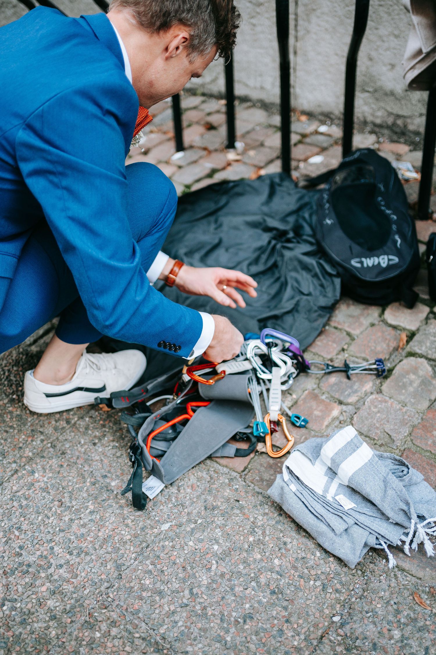 Brudgum förbereder klätterutrustning på gatan i stadsmiljö i Göteborg, bröllopsfotografering