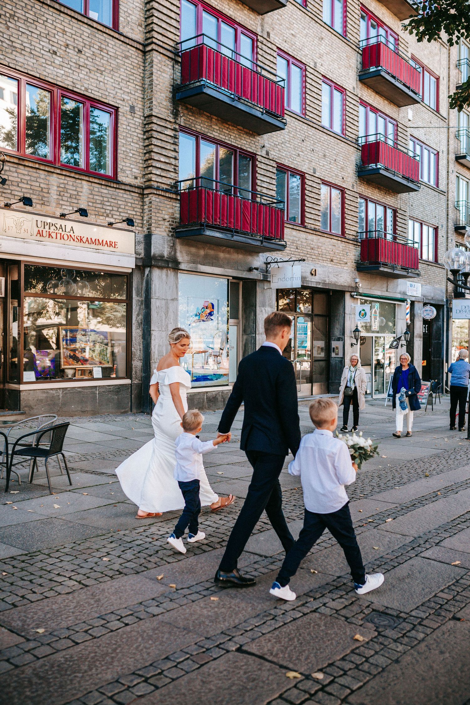 brudpar går över avenyn i göteborg med sina två barn påväg till vigsel i rådhuset, bröllopsfotografering, stadsbröllop