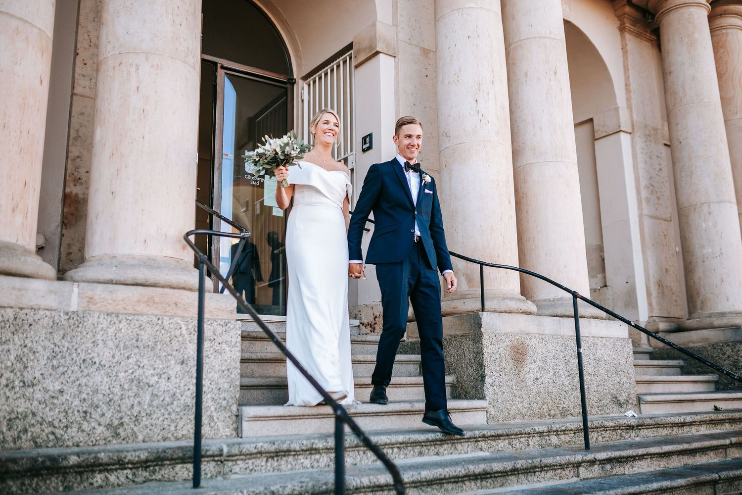 nygift kvinna och man går ut ur rådhuset i göteborg, för att mötas av gratulationer av gäster, bröllopsfotografering