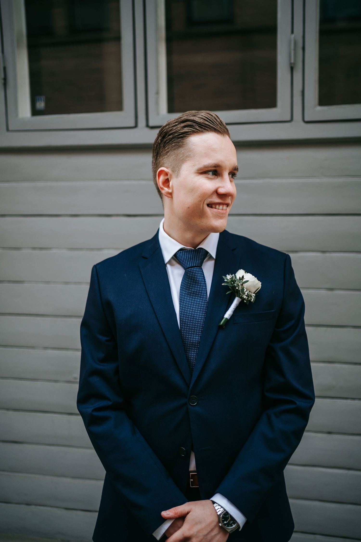 Brudgum ler i mörk kostym på kullerstensgata nära rådhuset i Göteborg, bröllopsfotografering