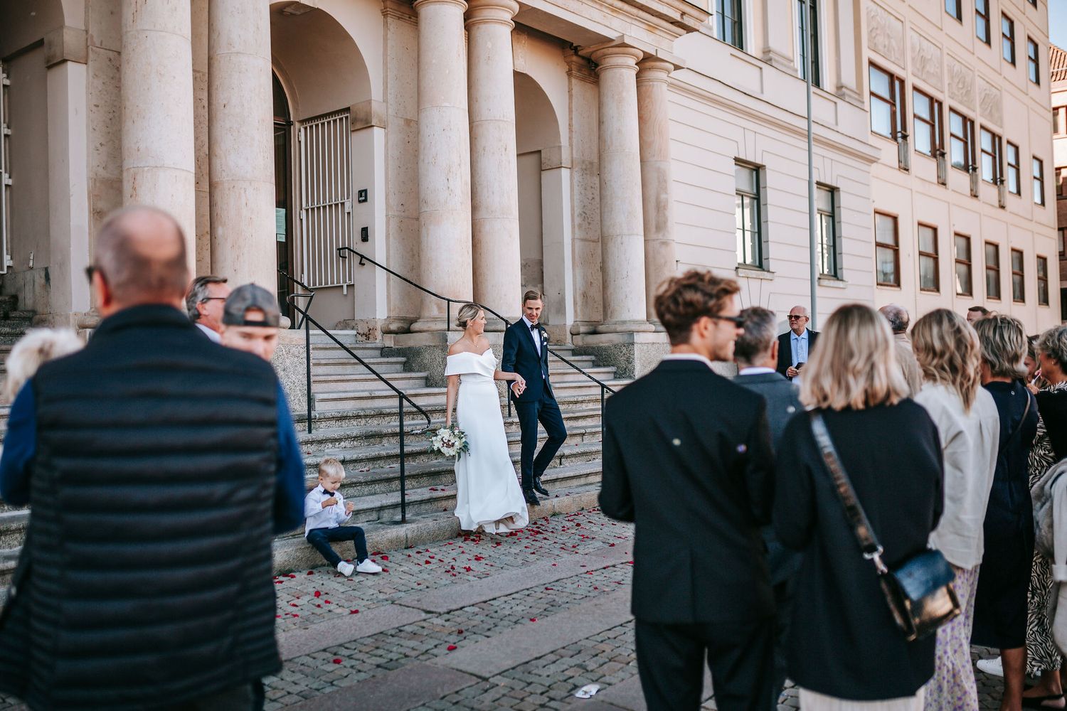 nygift kvinna och man går ut ur rådhuset i göteborg, för att mötas av gratulationer av gäster, fotografering bröllop, bröllopsfotografering