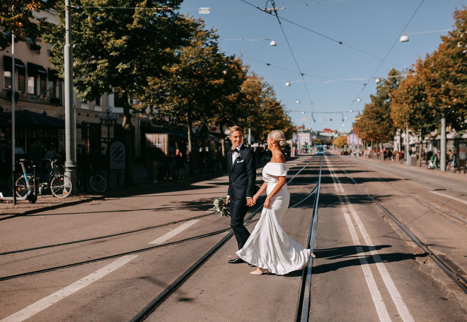 brudpar går över avenyn i göteborg på spårvagnsspåren, västkustbröllop, stadsbröllop, bröllopsfotografering