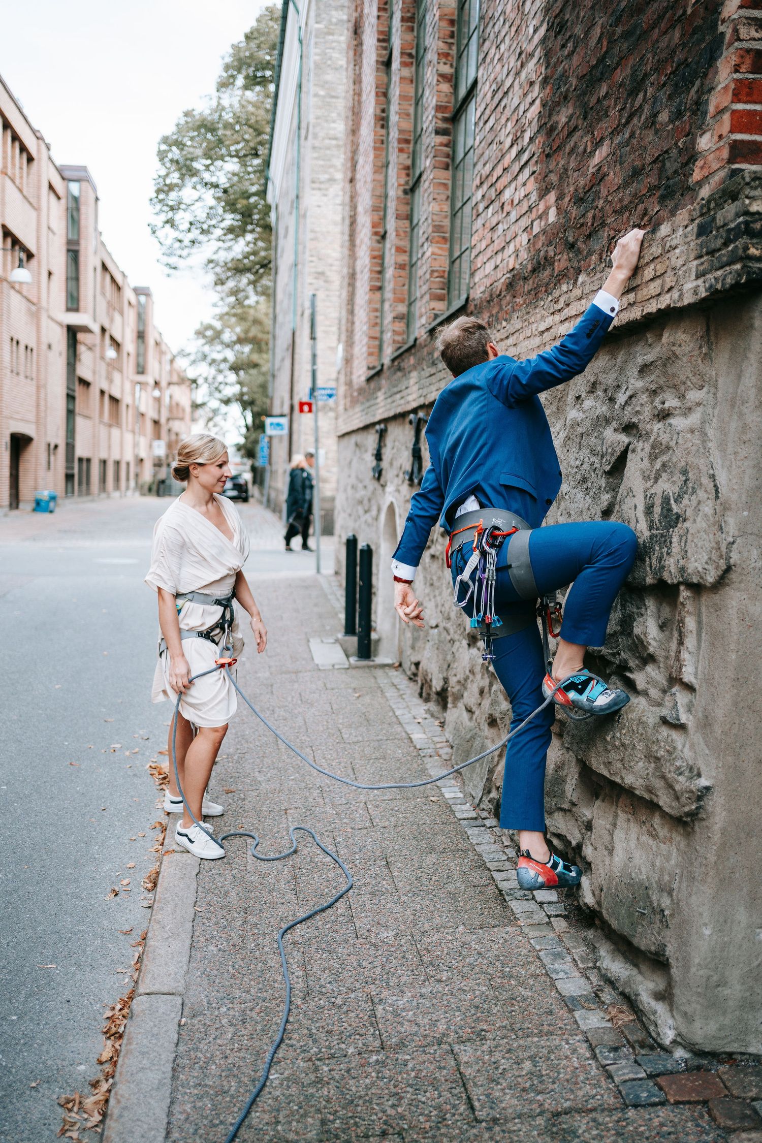 brudgum klättrar på stenmur med rep i stadsmiljö i Göteborg, annorlunda bröllopsfotografering