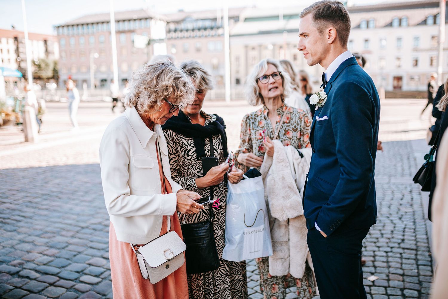 gäster till bröllop i rådhuset i göteborg som gratulerar brudparet, bröllopsfotografering mingel utanför stadshuset