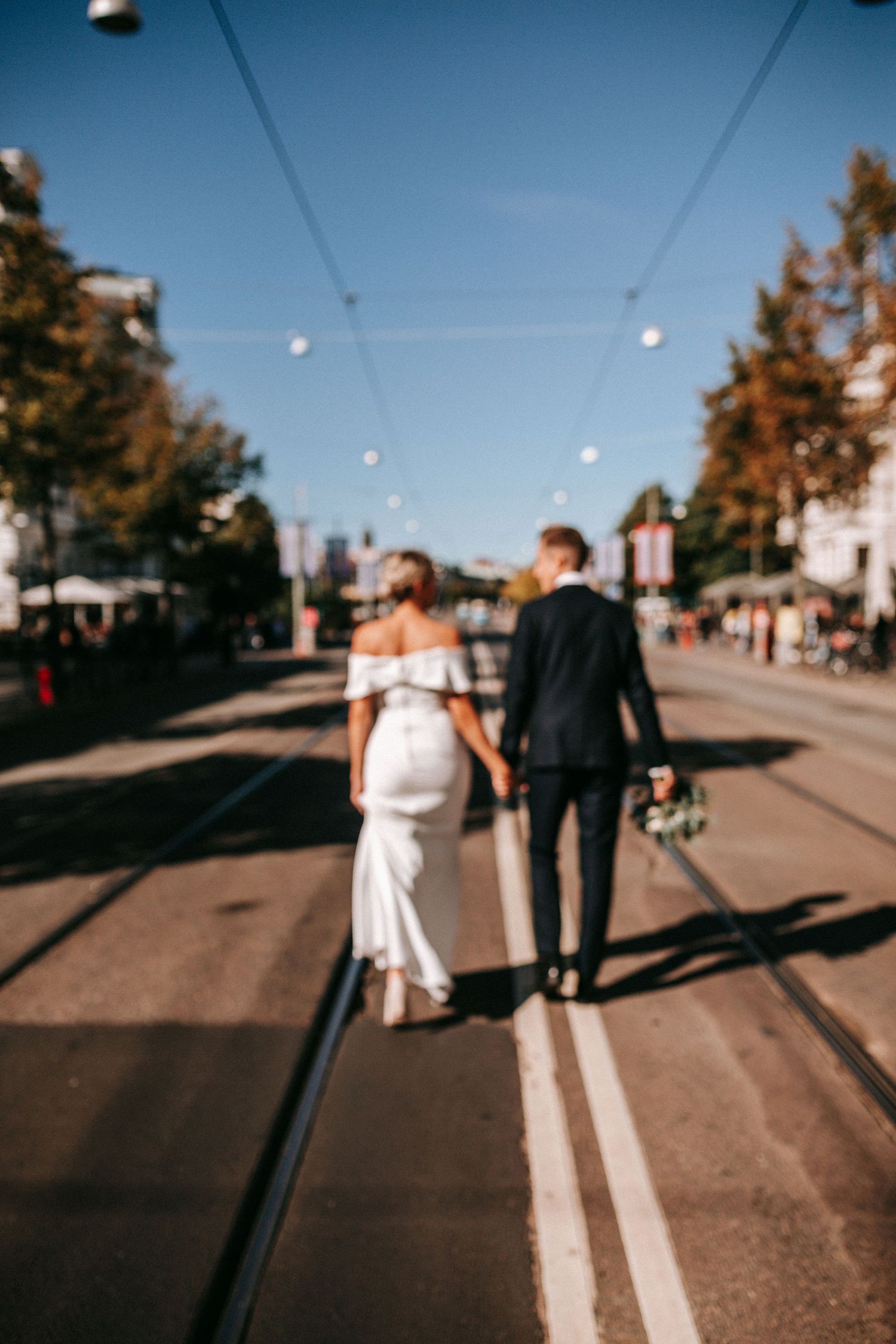 dokumentär bild på brudpar som går längst med spårvagnsspåren på avenyn, bröllopsfotografering