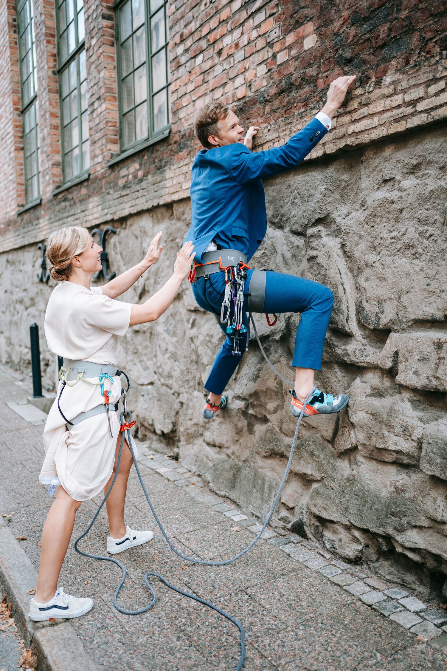brudgum klättrar på stenmur med rep i stadsmiljö i Göteborg, bröllopsfotografering