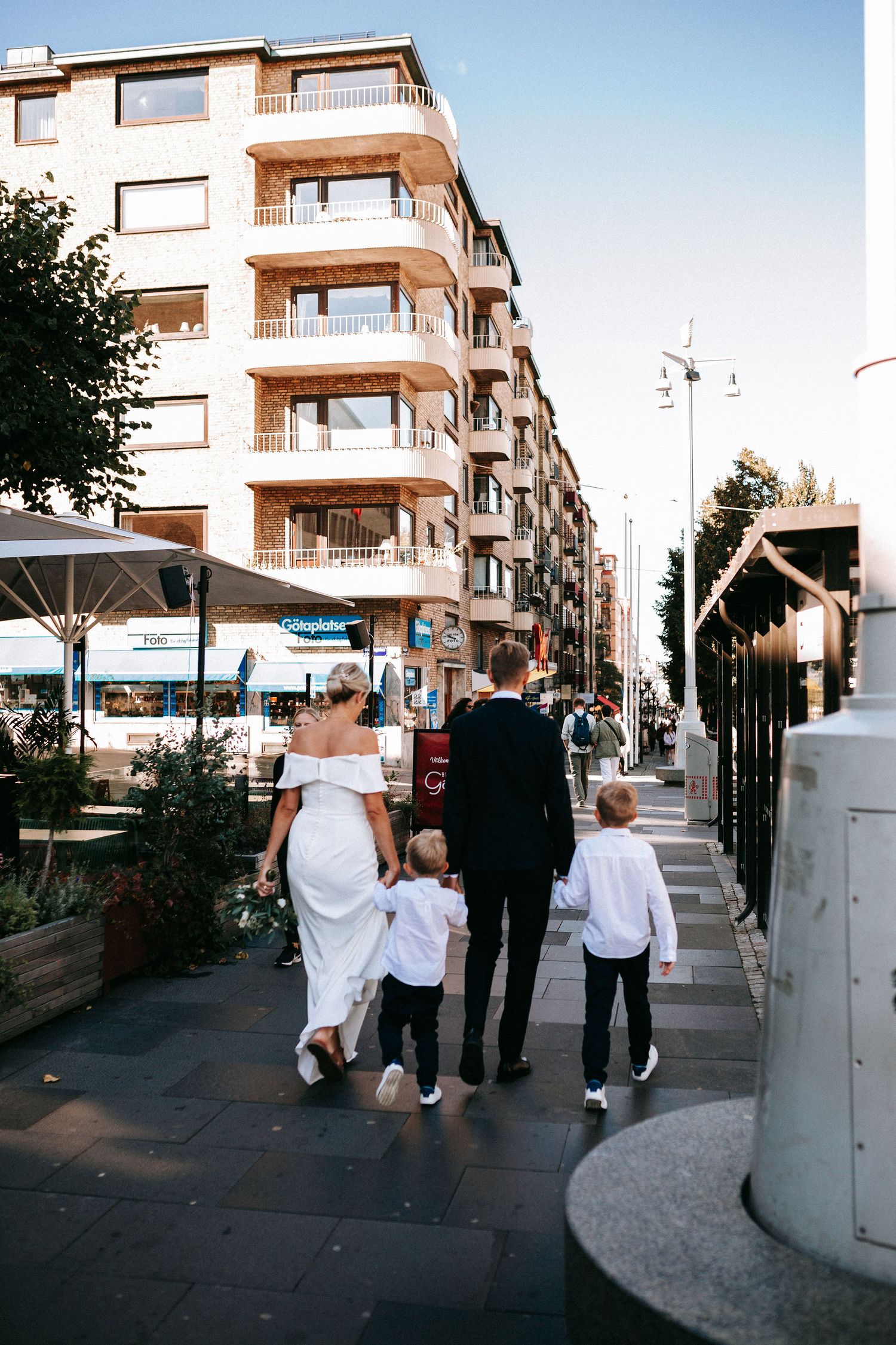 brudpar går över avenyn i göteborg med sina två barn påväg till vigsel i rådhuset, bröllopsfotografering mitt i stan