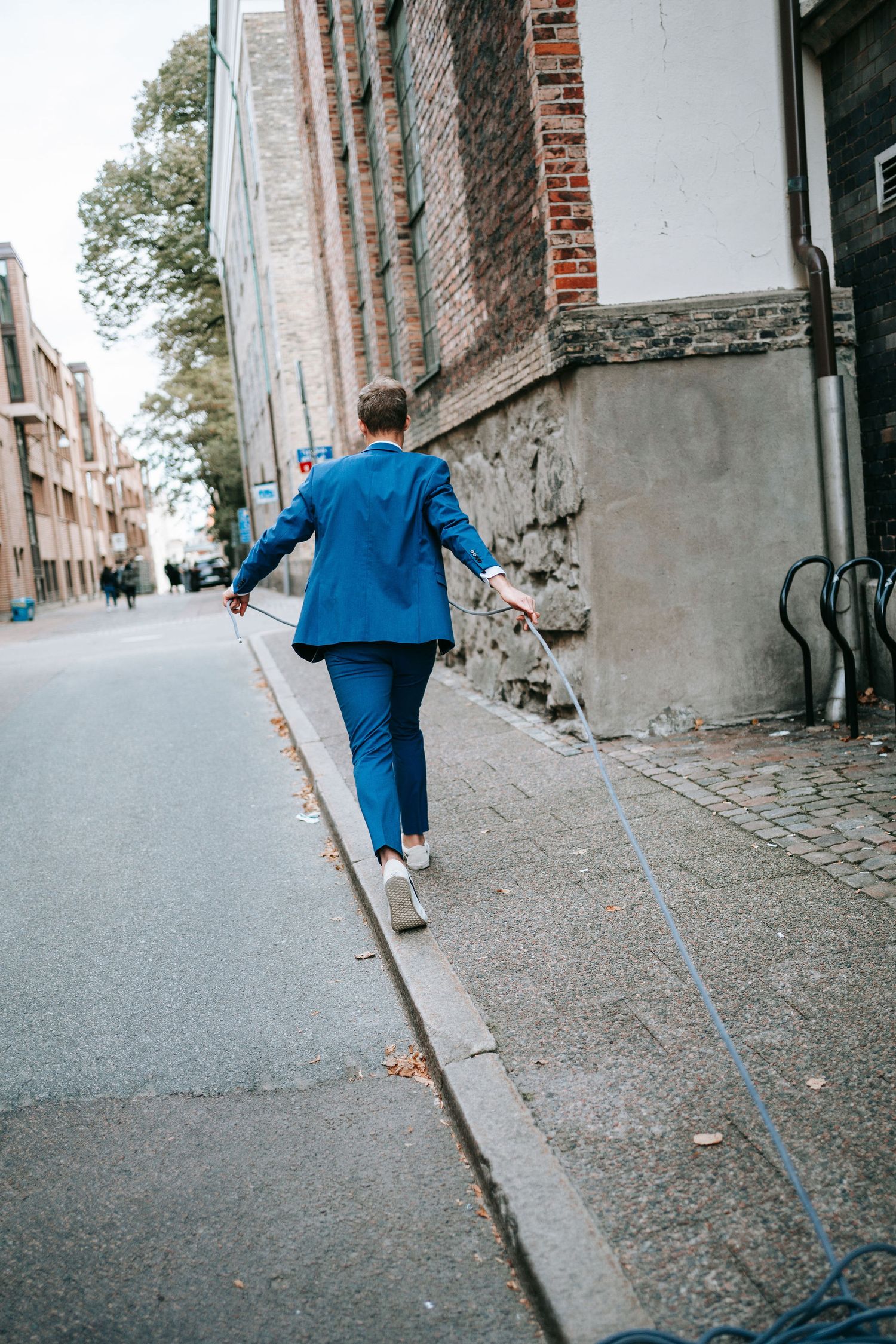 Brudgum förbereder klätterutrustning på gatan i stadsmiljö i Göteborg, fotograf bröllop