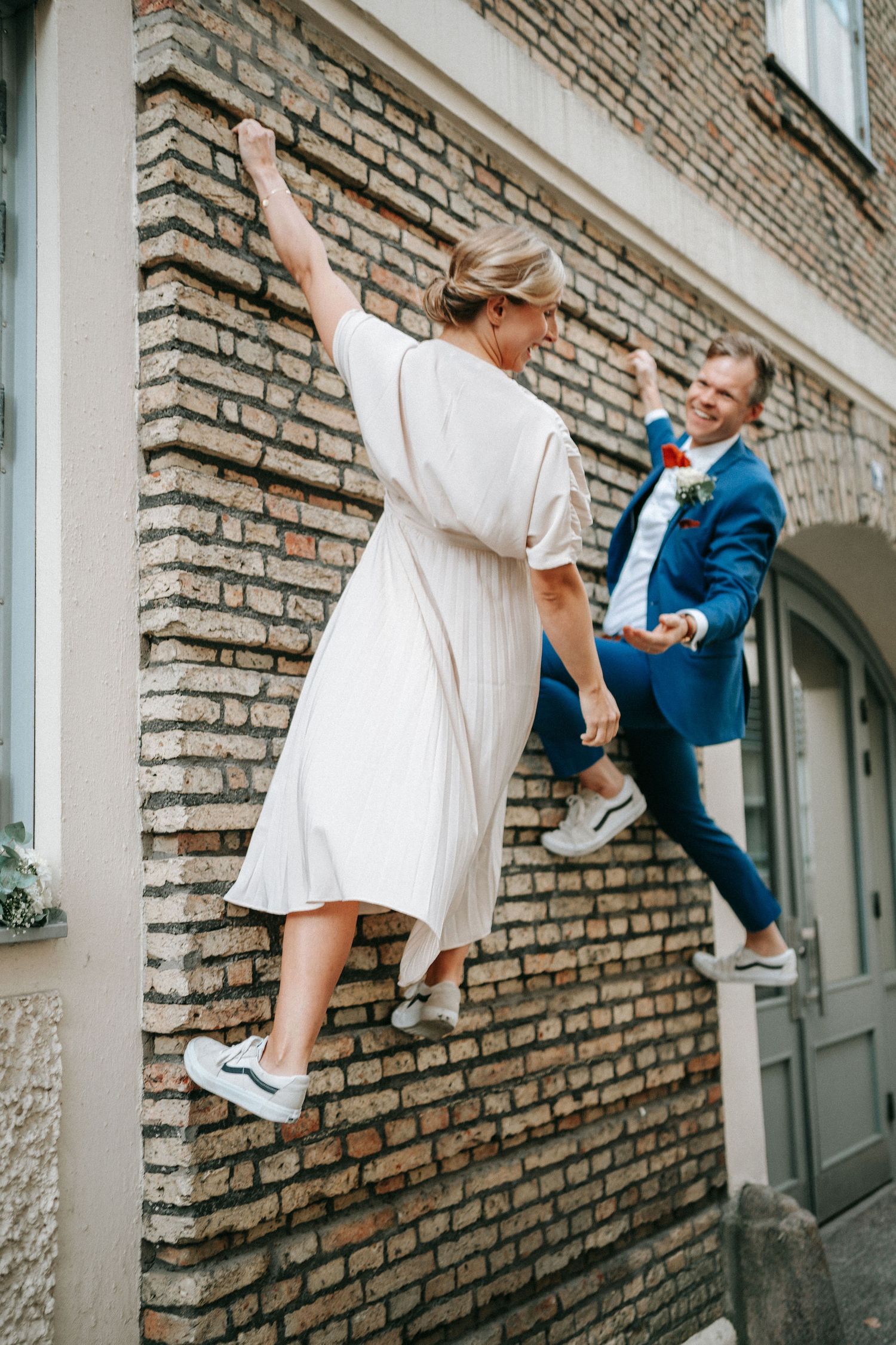brudpar som klättrar på tegelvägg i stadsmiljö i Göteborg, bröllopsfotografering