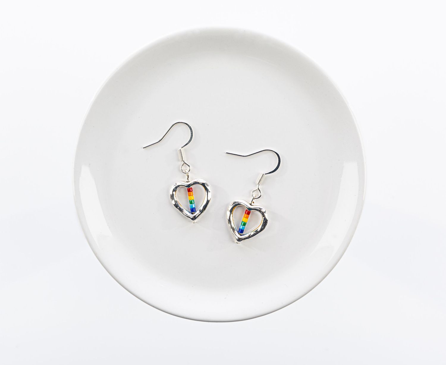 Image of silver earrings with rainbow styled beads in the middle. Photos of products that a company will be selling on their website.