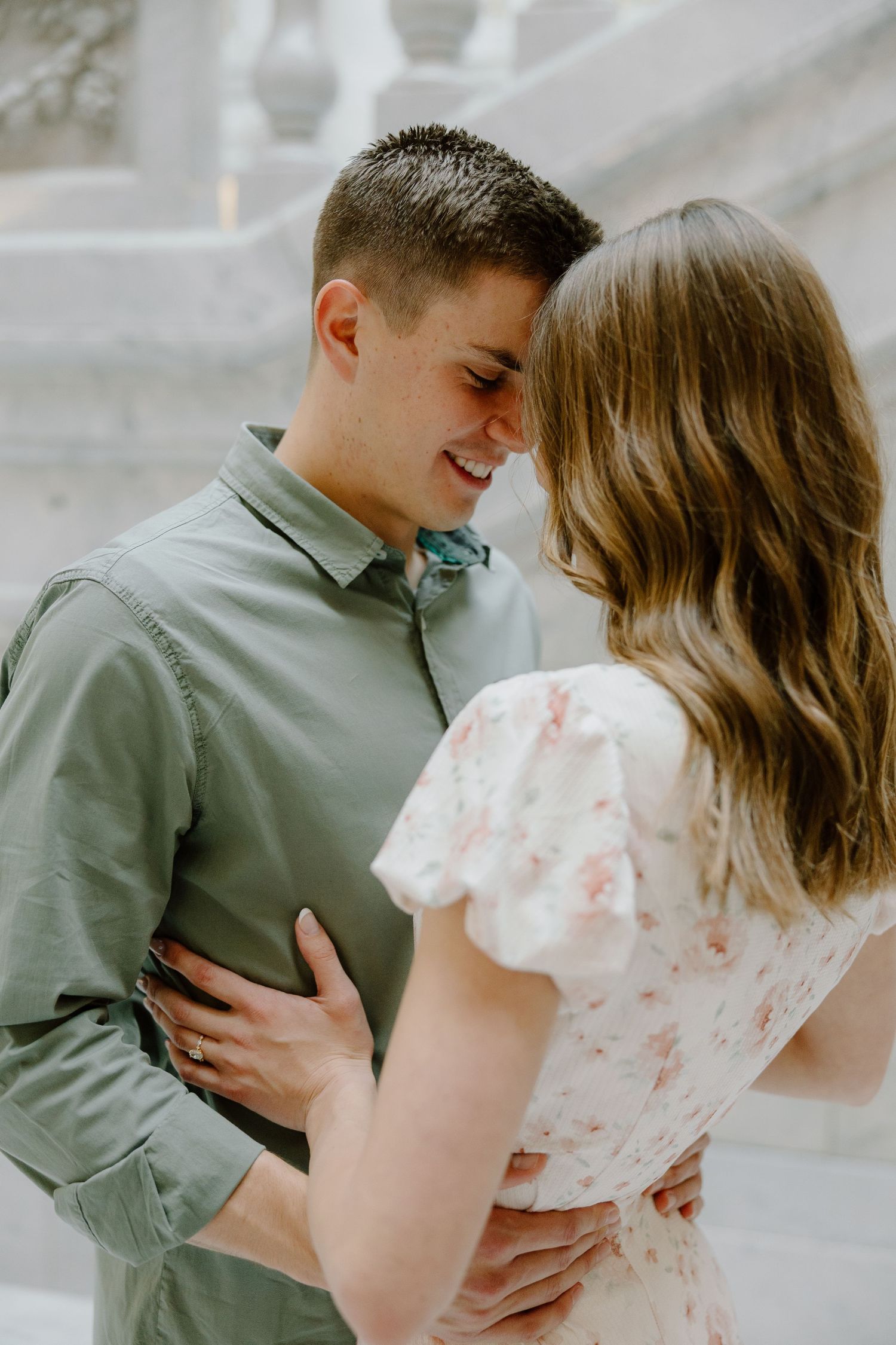 Close-up of smiling young couple in a tender forehead-to-forehead moment during engagement photos.