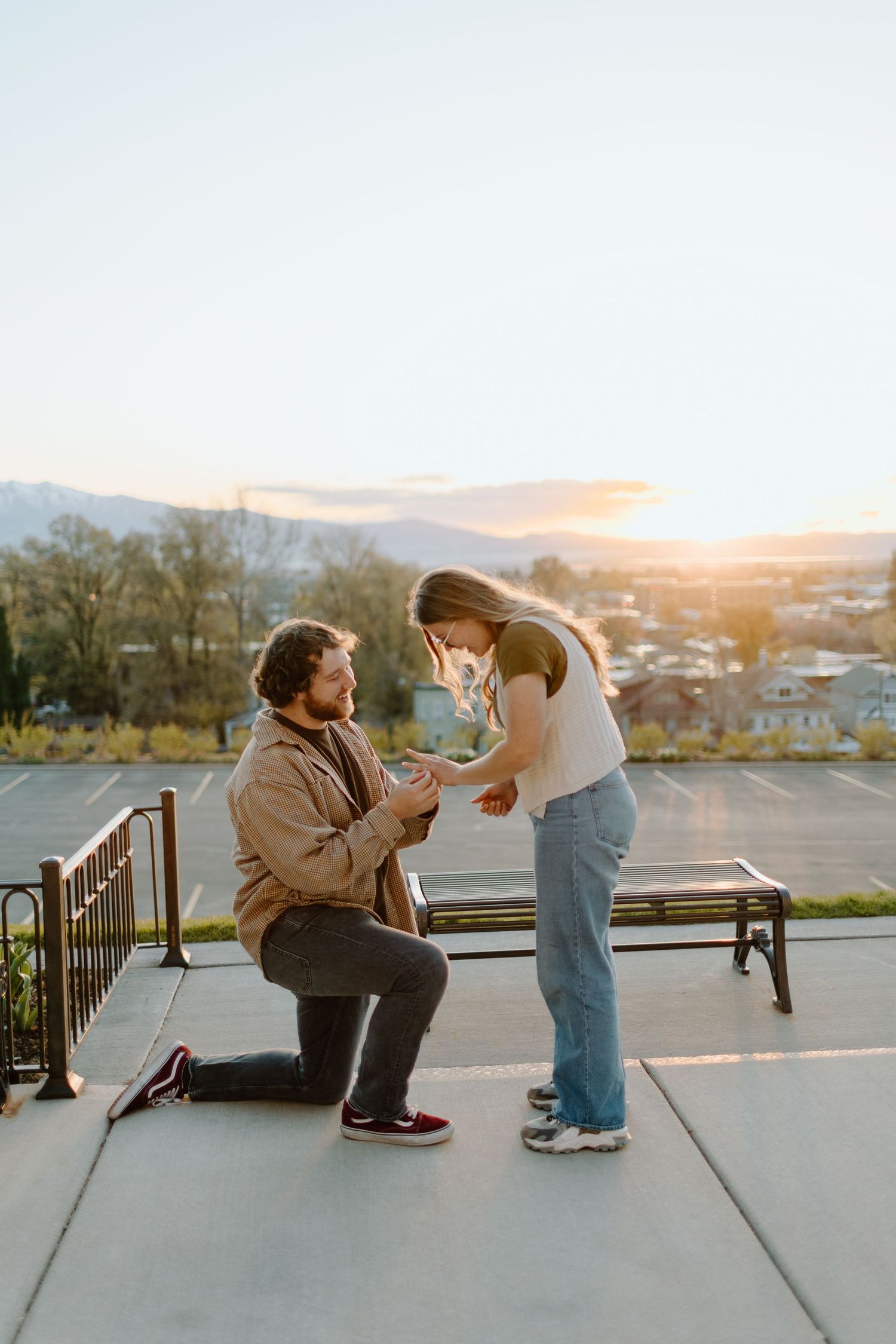 A proposal scene unfolds on a concrete overlook during sunset.