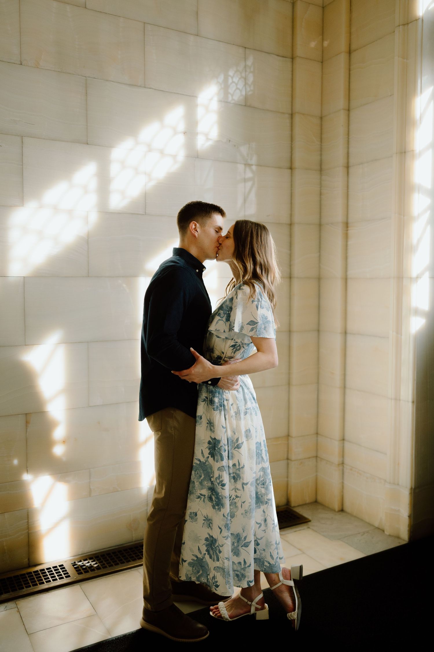 A romantic couple shares intimate moments in a sunlit room with white walls.
