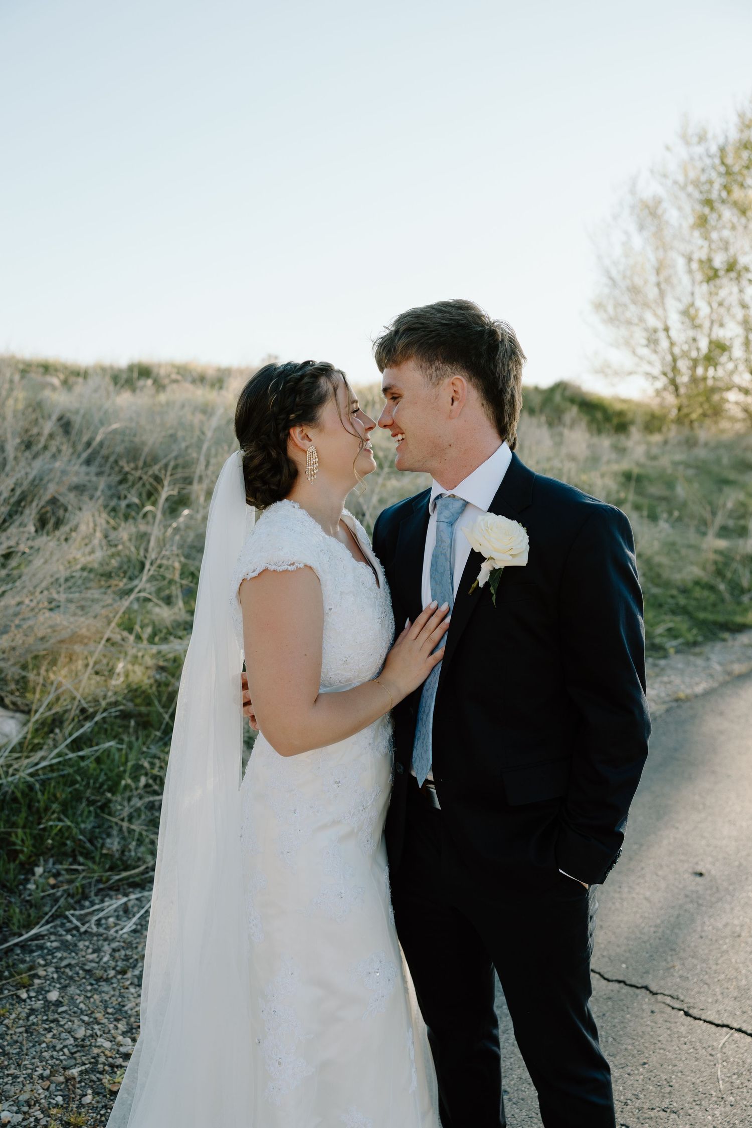 Bride and groom share a tender nose-to-nose moment on a rustic outdoor pathway.