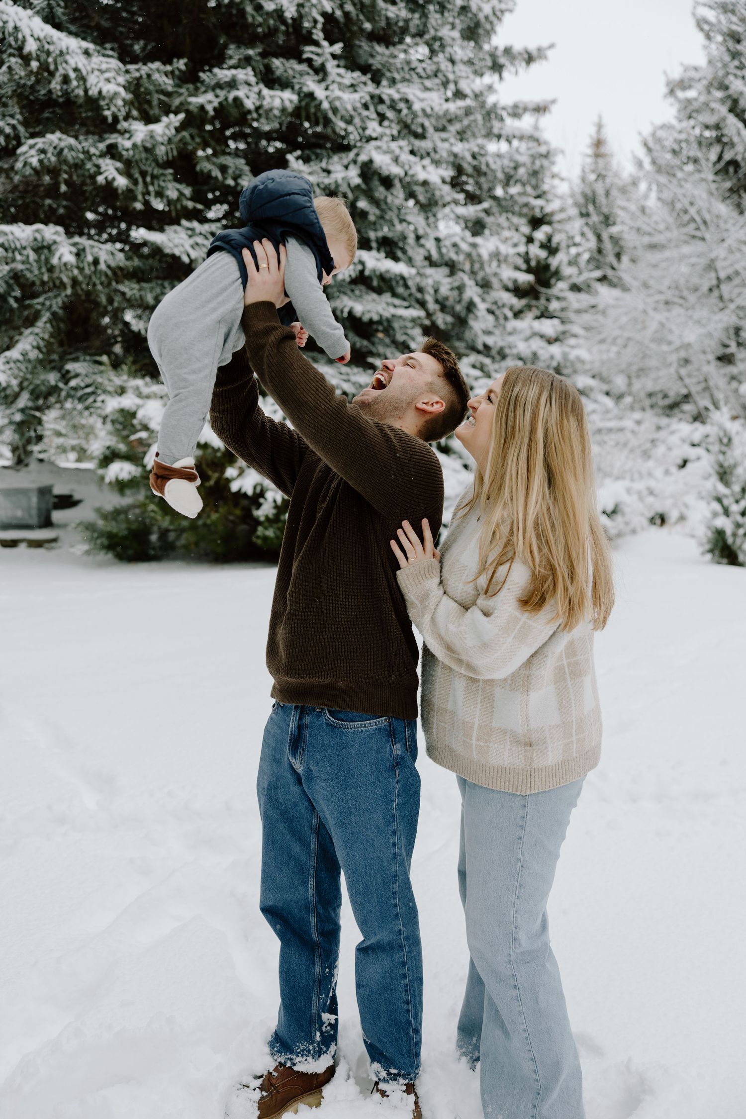 A joyful winter photoshoot among snow-covered pine trees.