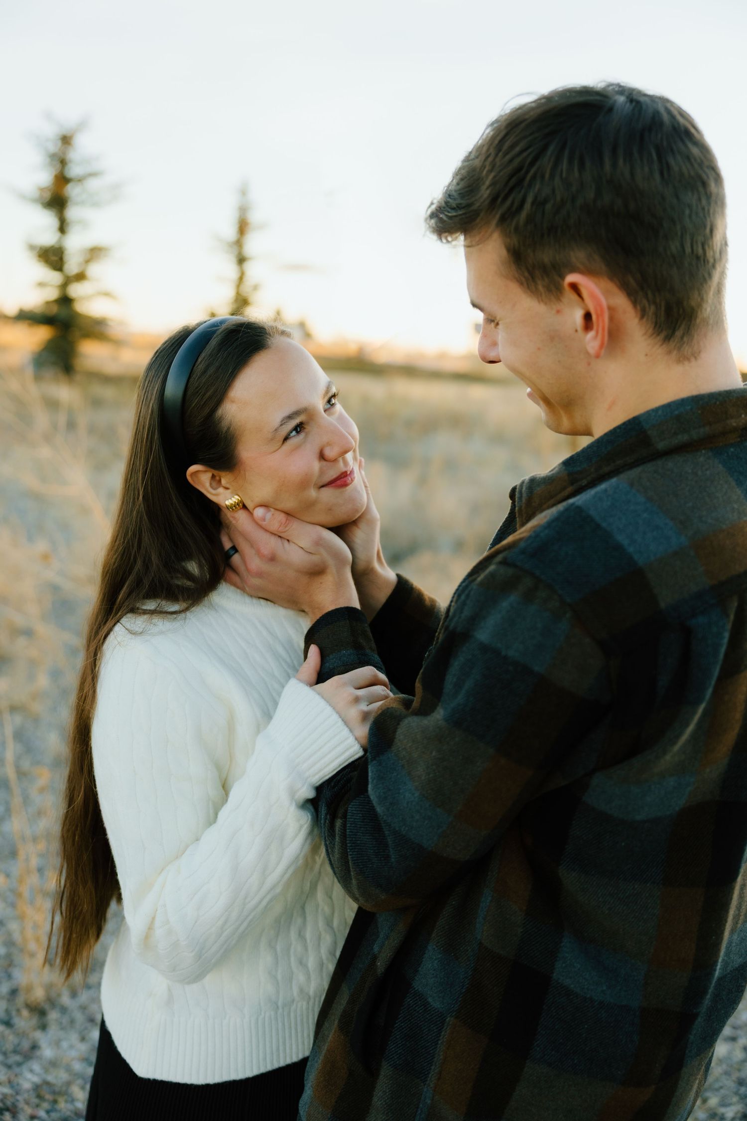 A couple in winter clothing embraces outdoors during a romantic photoshoot.