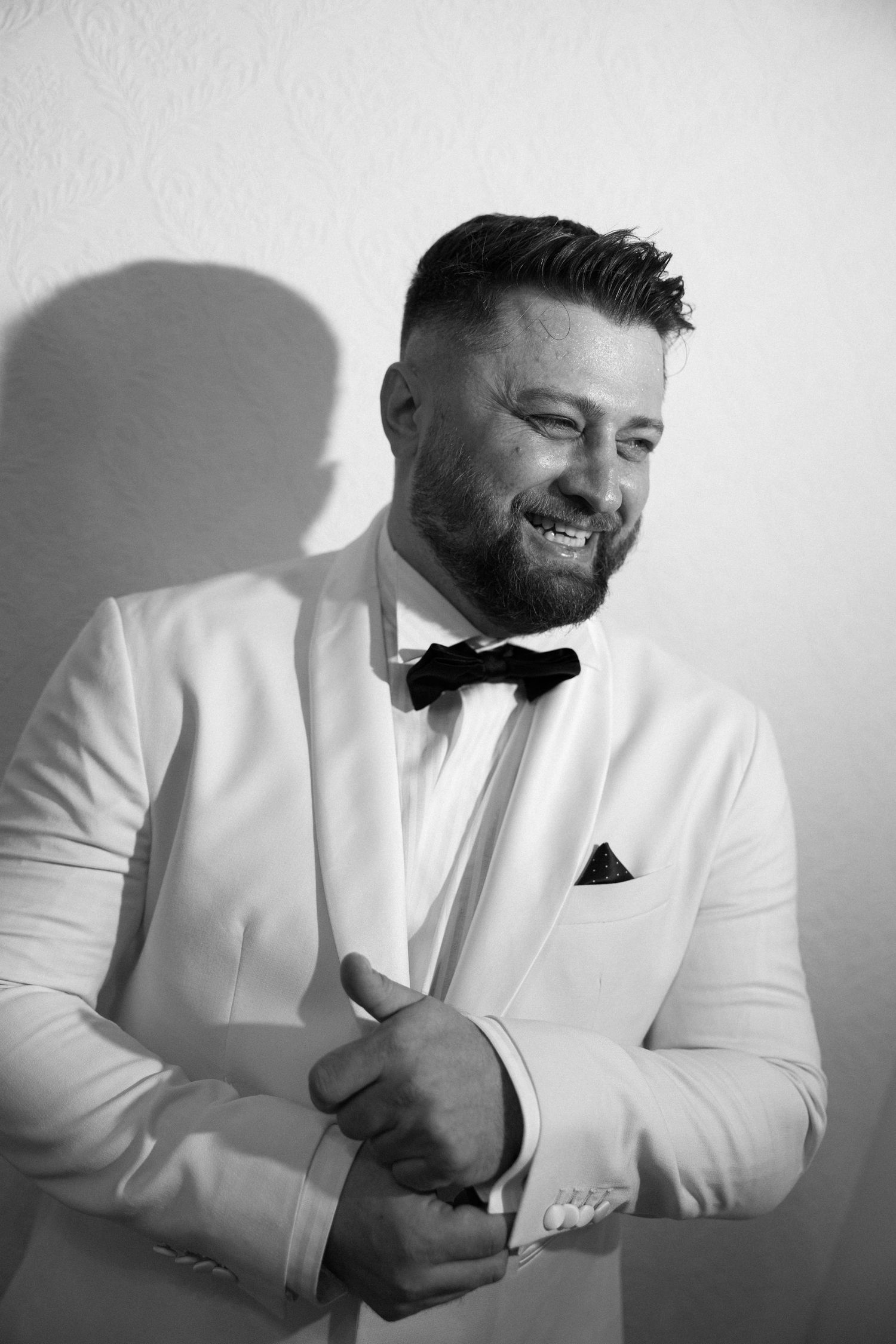 A series of black and white photos showing someone in a white suit jacket laughing and gesturing expressively.