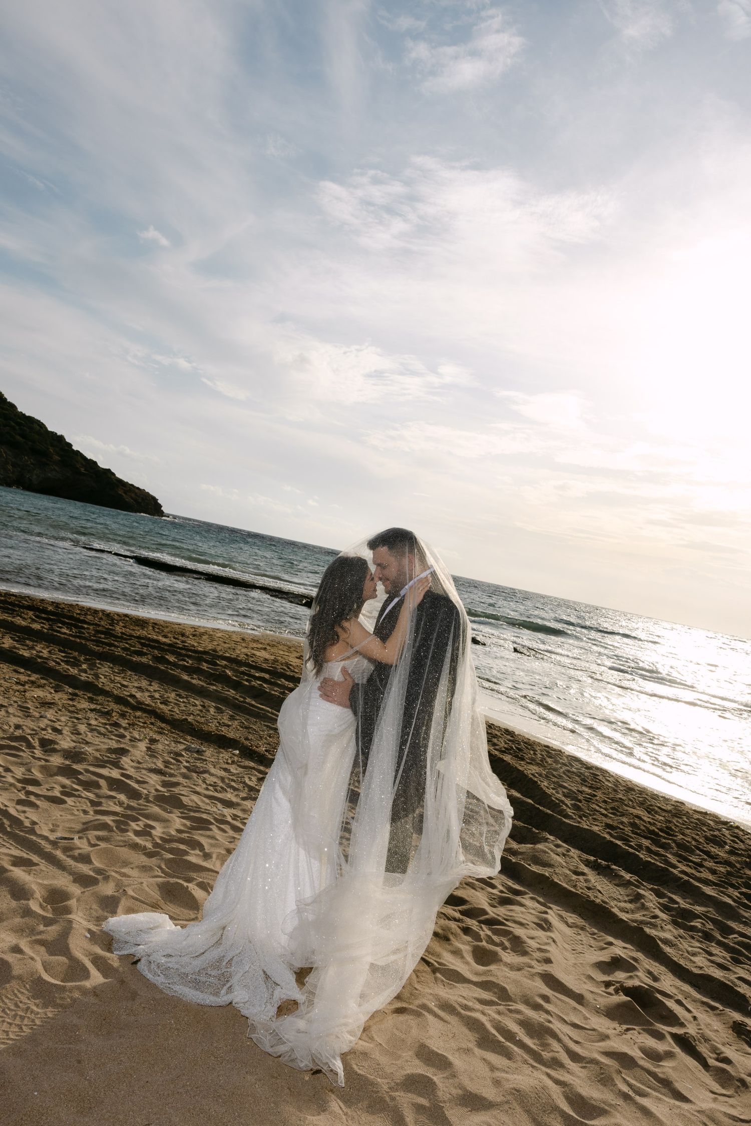 A romantic beach wedding photo series showing a couple in flowing white attire against an ocean backdrop at sunset.
