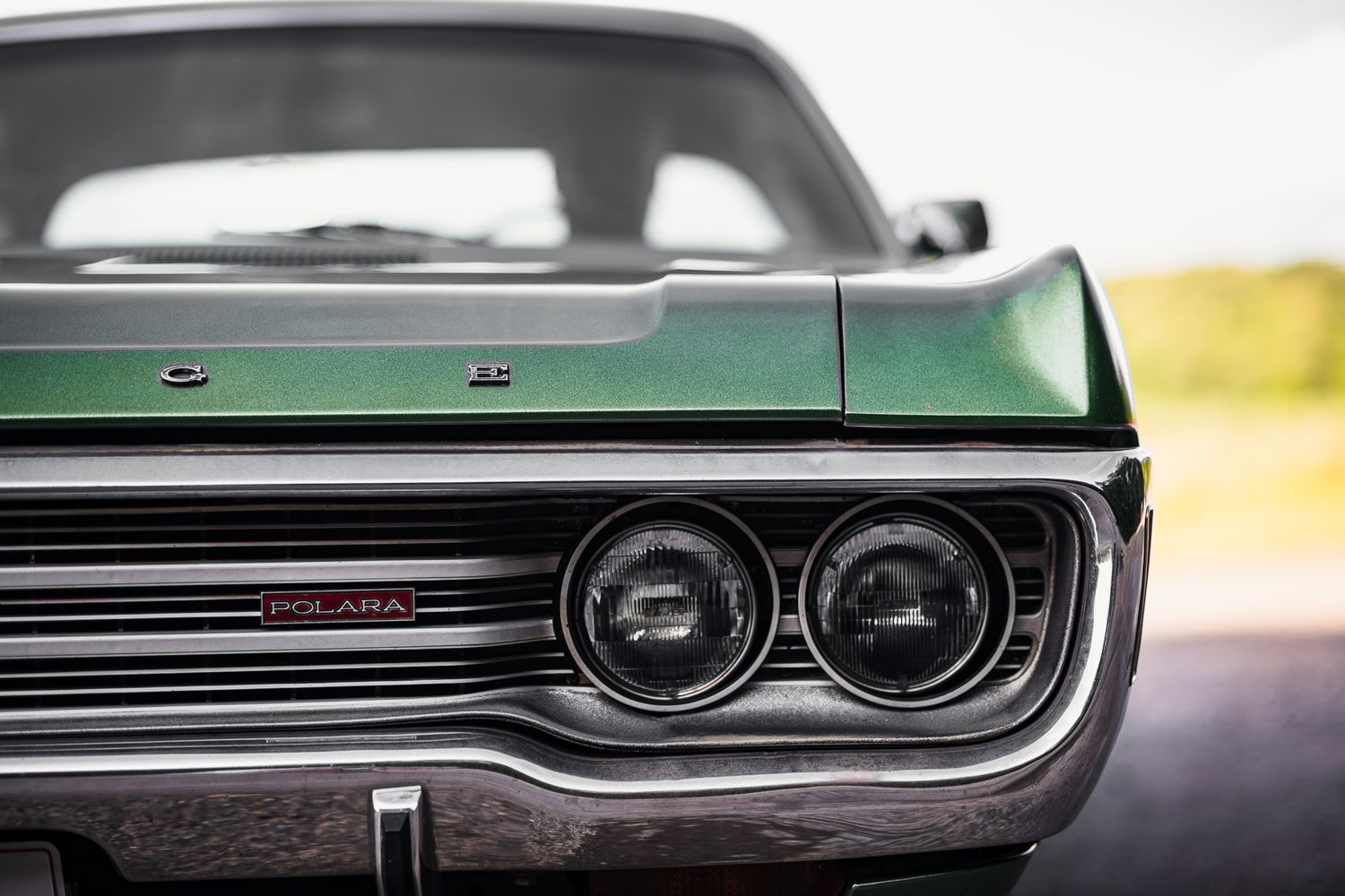Close-up of a green Dodge Polara classic car front headlights and grille detail.