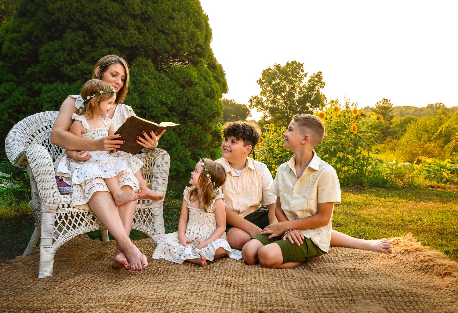 A mother reads a book to her three children on a picnic blanket in a sunny garden at golden hour.