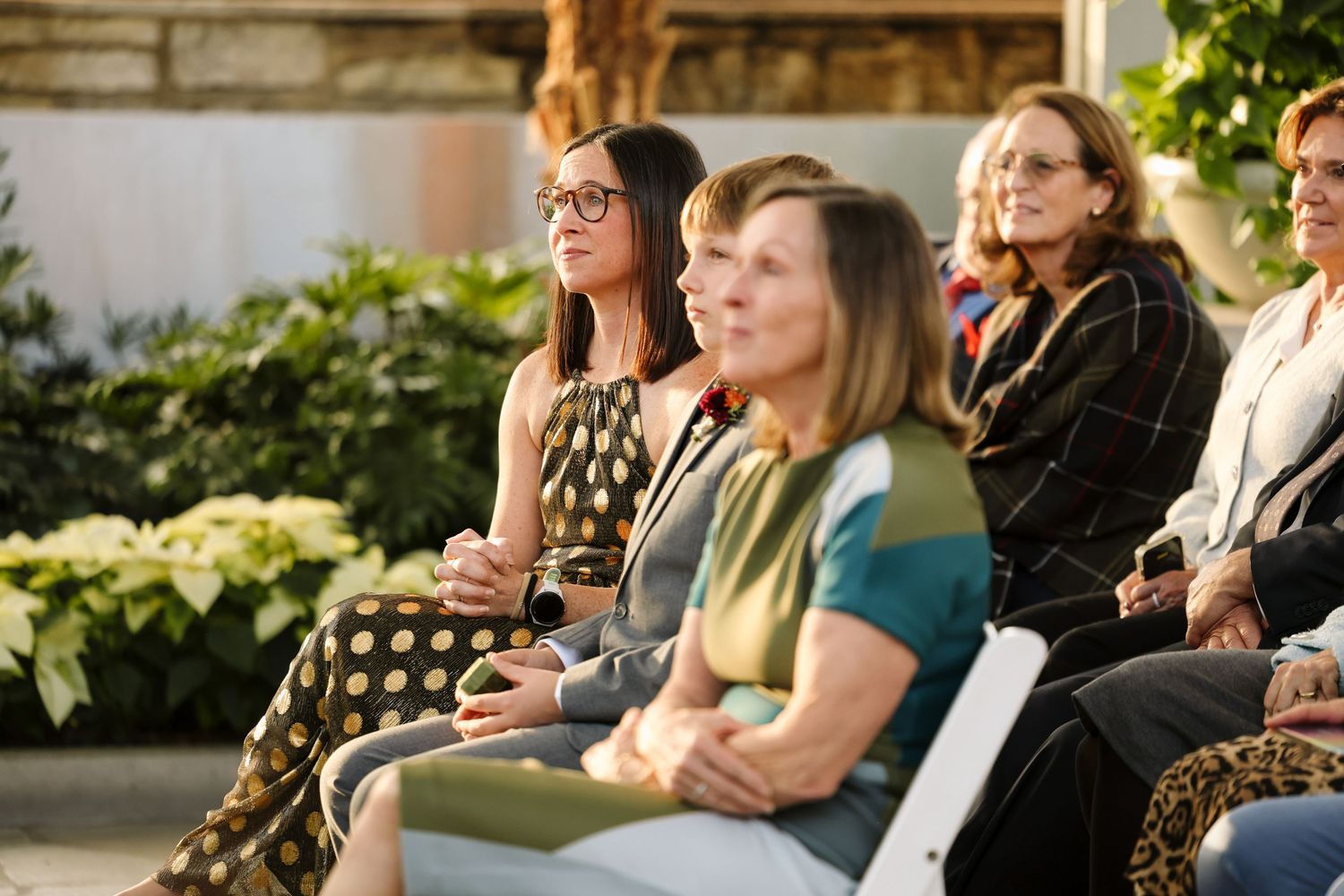 Group of women seated outdoors at a dreamy garden wedding ceremony surrounded by soft smiles and happy tears.