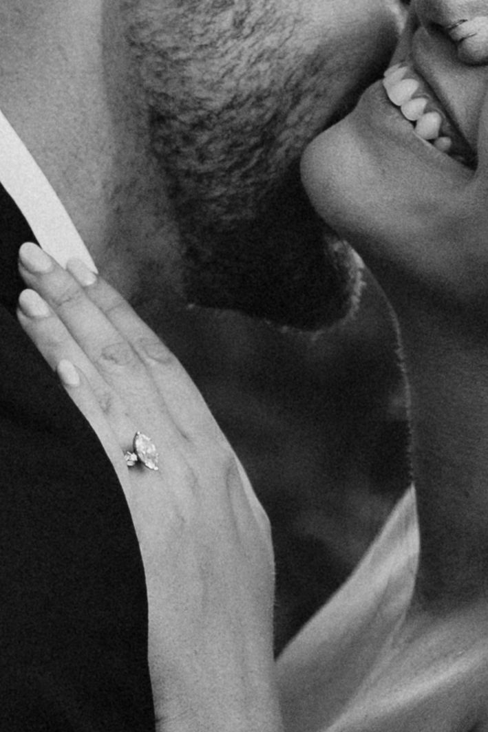 Close-up black and white photo of smiling bride wearing marquise diamond engagement ring.