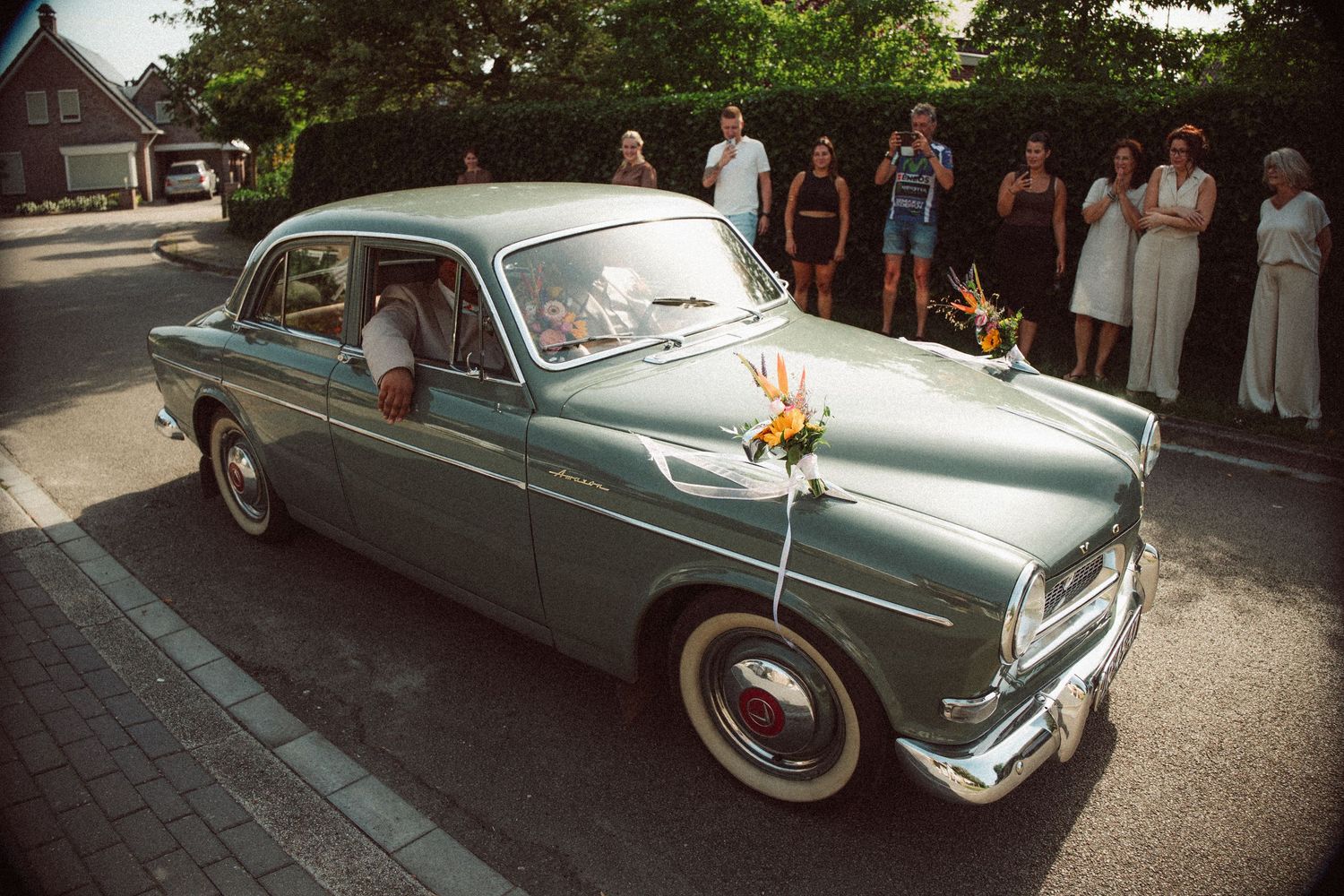 Vintage teal car decorated with flowers at a wedding ceremony.