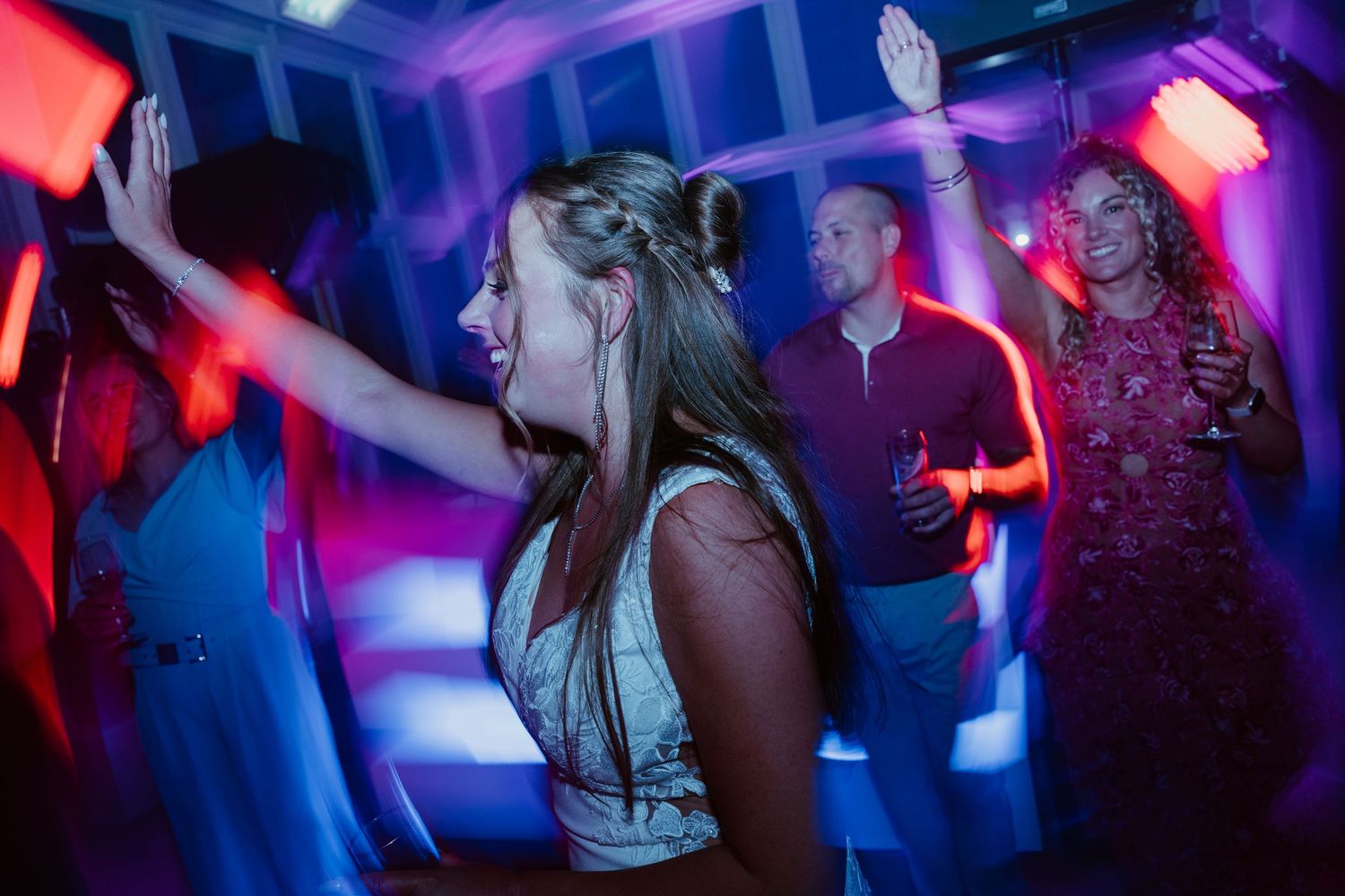 Woman dancing energetically at a vibrant nightclub party with colorful purple and blue lights.