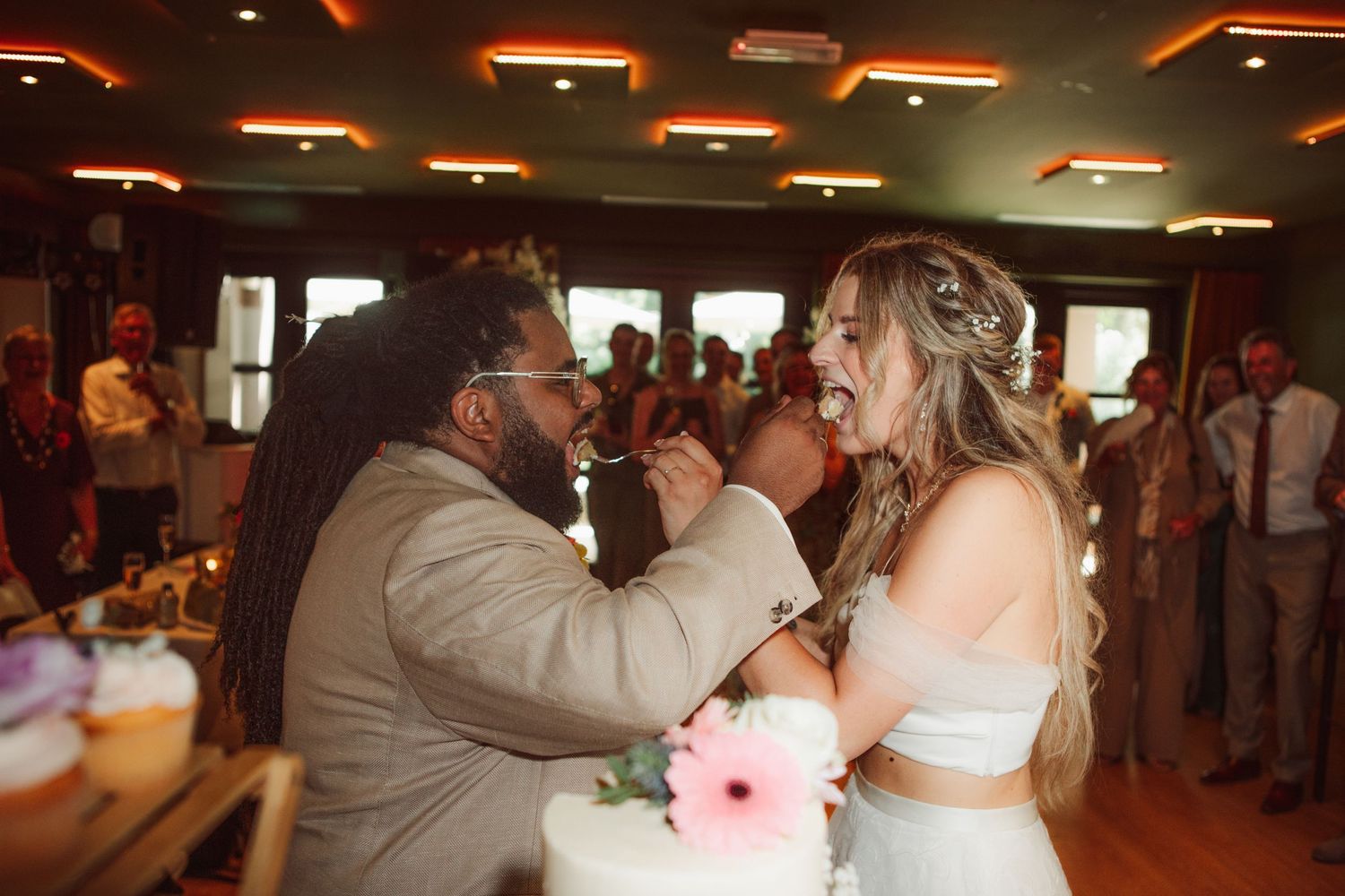 Bride and groom sharing cake at their wedding reception.