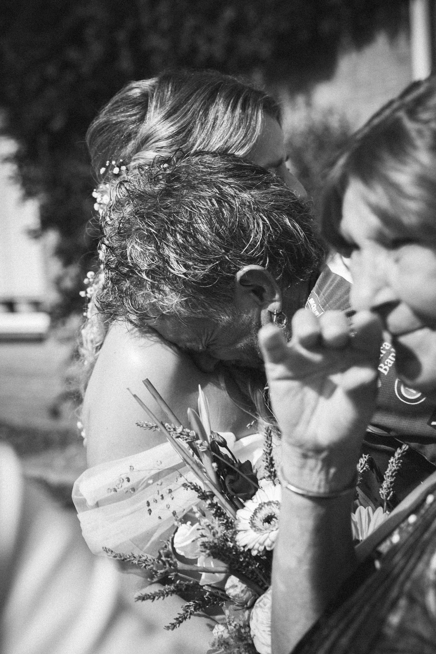 Black and white candid photo of bride with floral hair accessories at wedding.