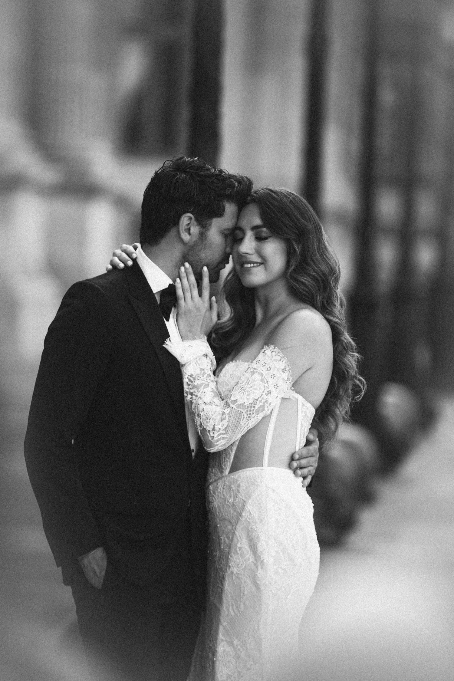 Black and white romantic portrait of a groom tenderly kissing his smiling bride in Paris.