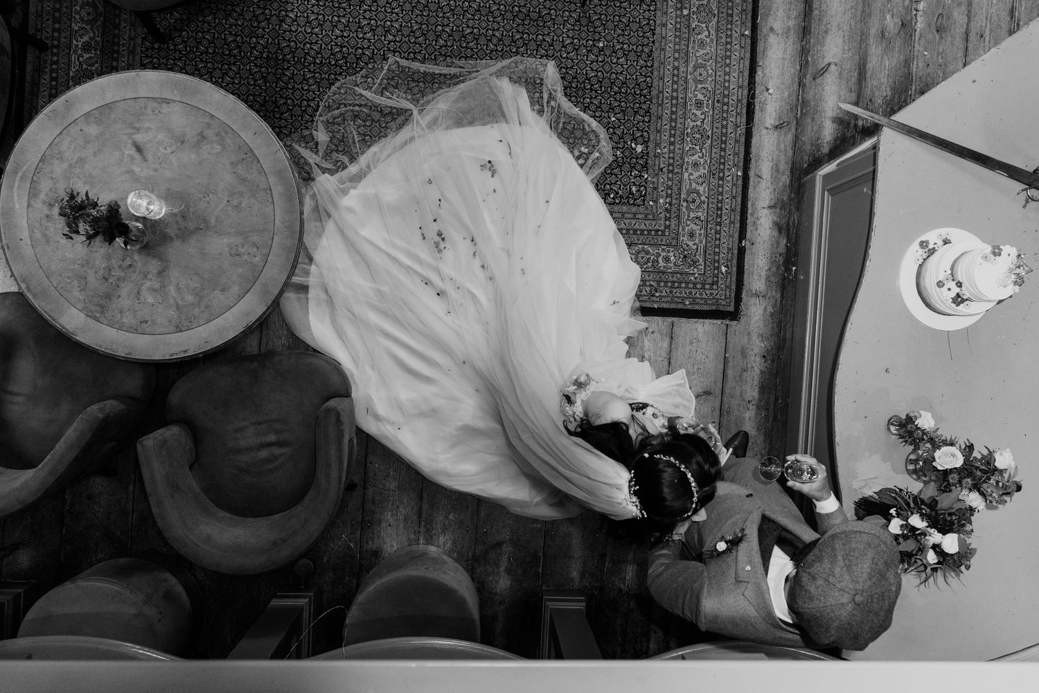 Black and white artistic flat lay of bridal veil and wedding bouquet with roses on decorative wooden surface.