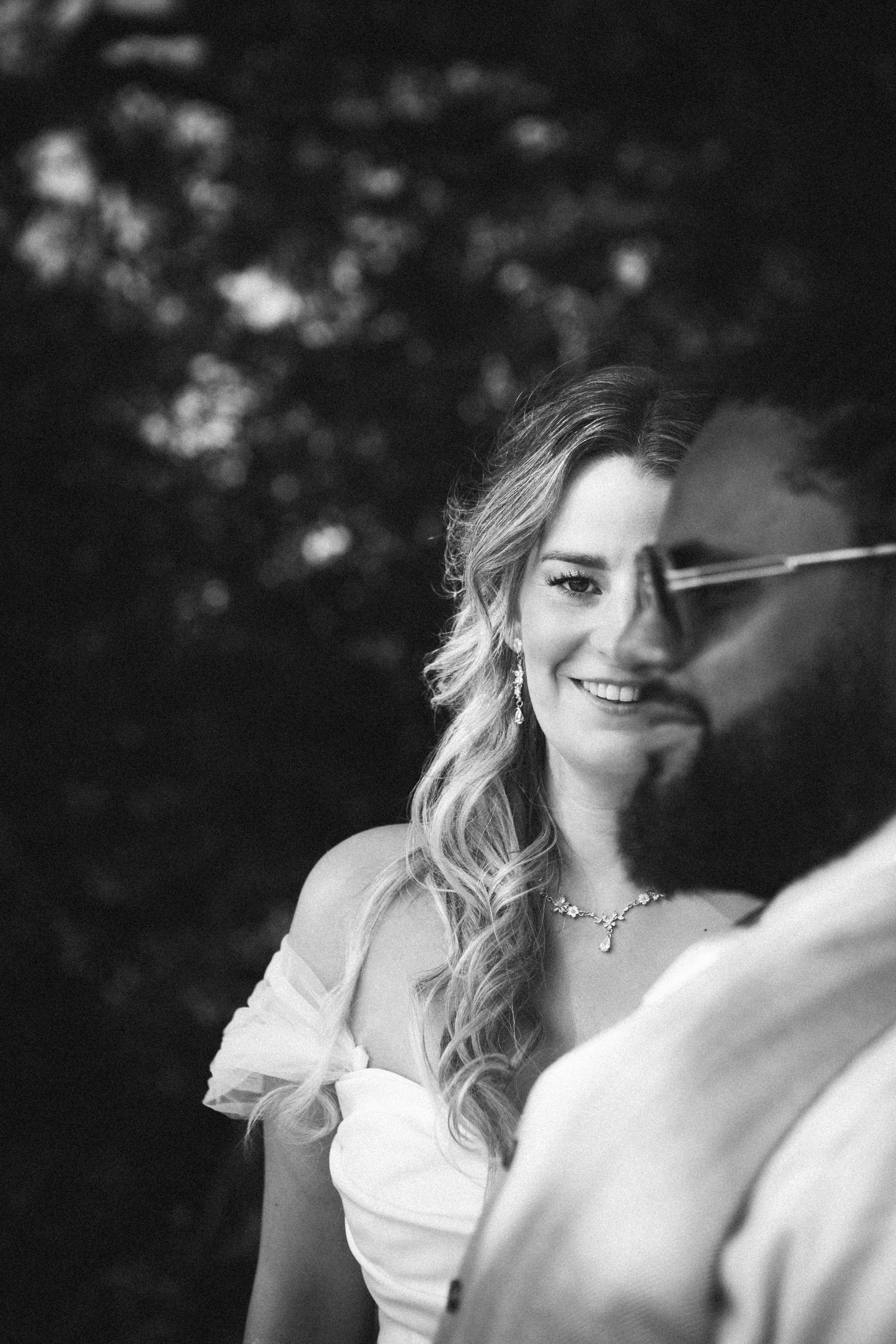 Black and white portrait of smiling bride looking at groom.
