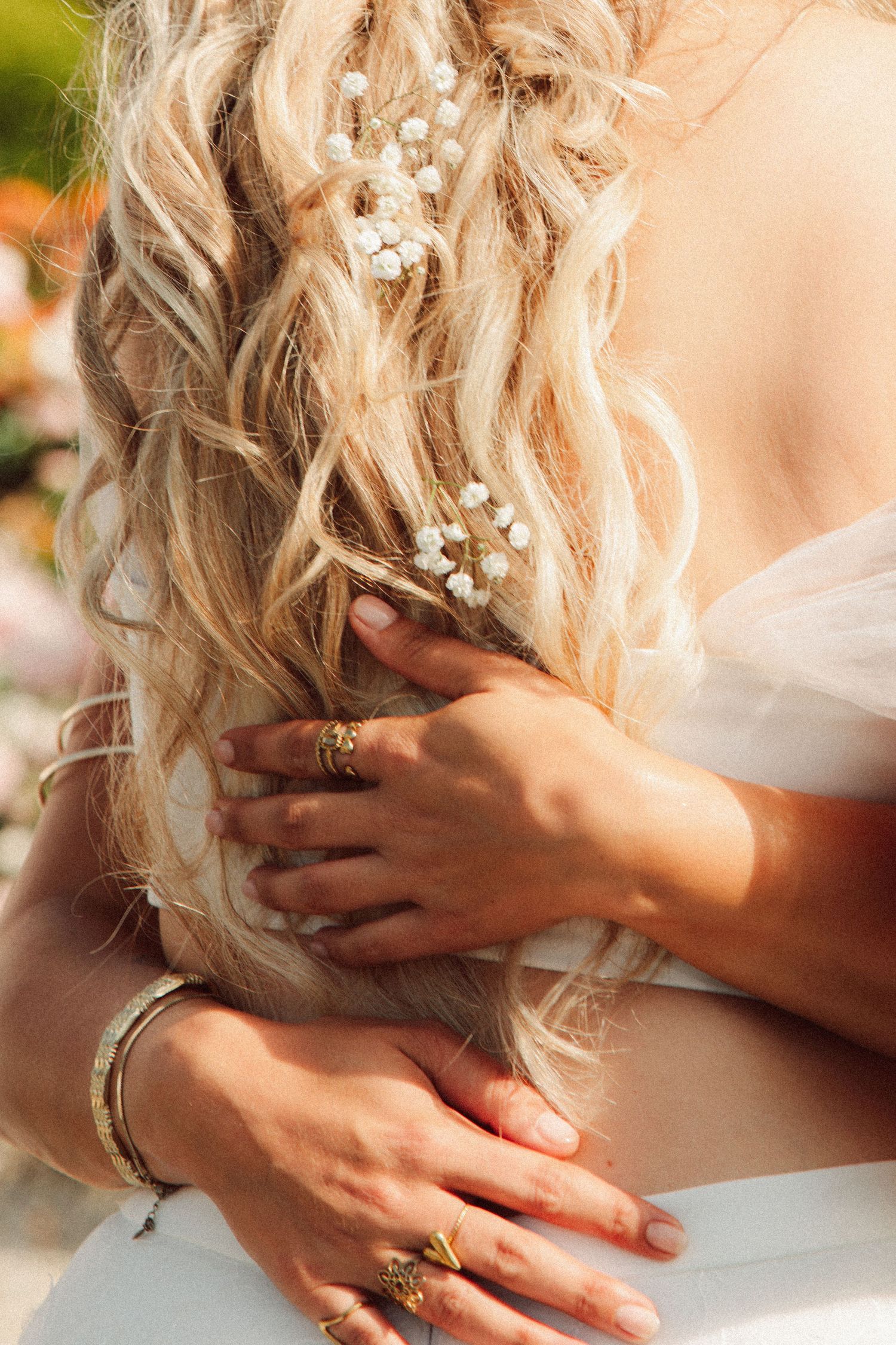 Close-up of bride with pearl hair accessories and gold rings on her back.