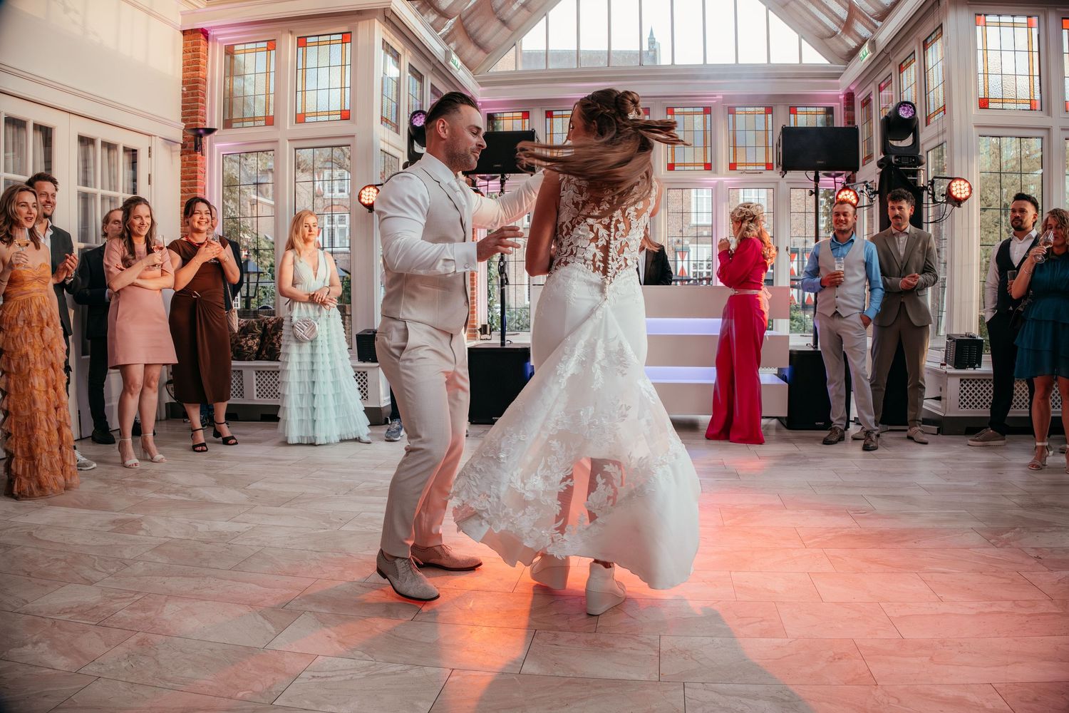 Bride and groom share their first dance in an elegant glass conservatory wedding venue.