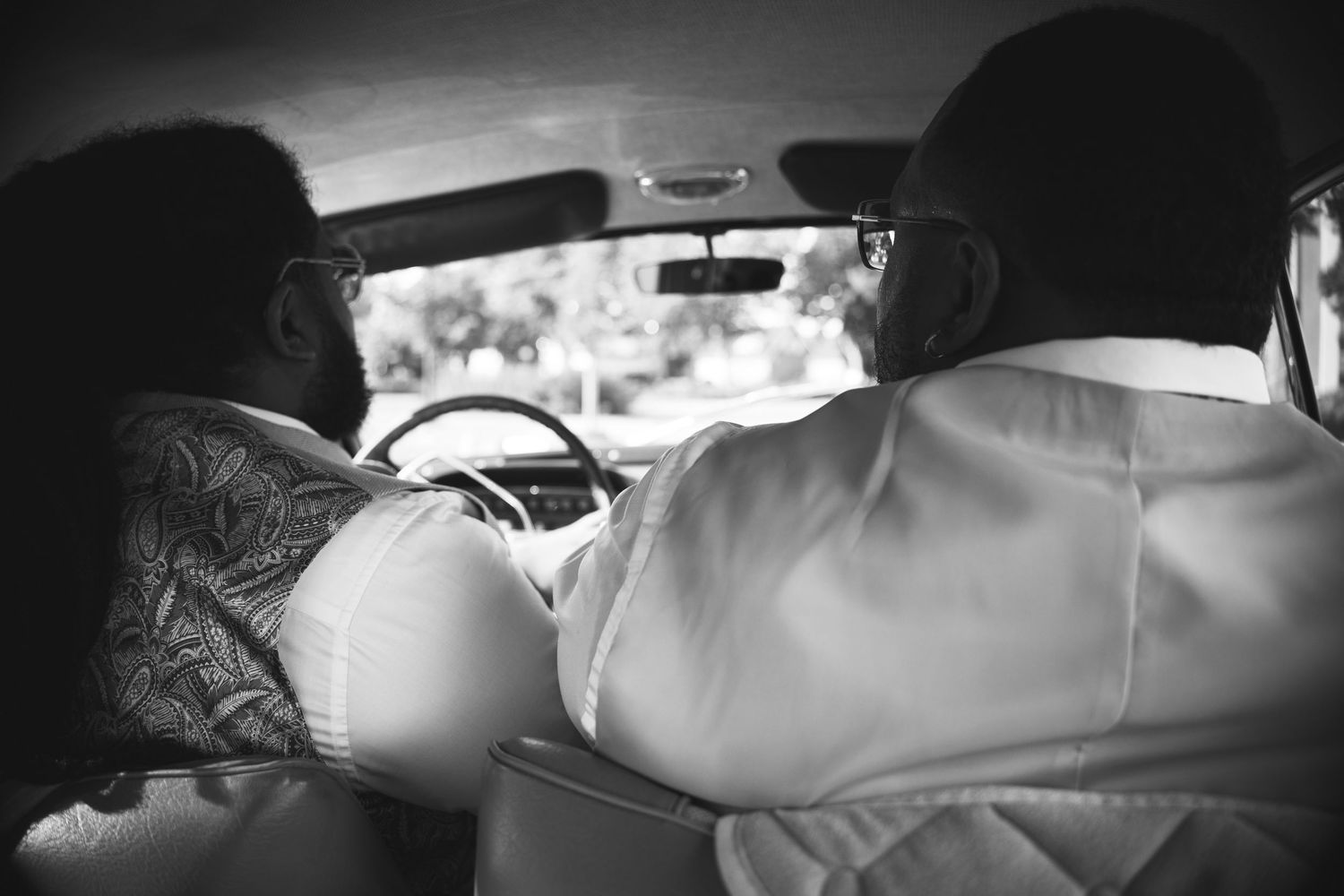Black and white photo of couple riding in a vintage car.