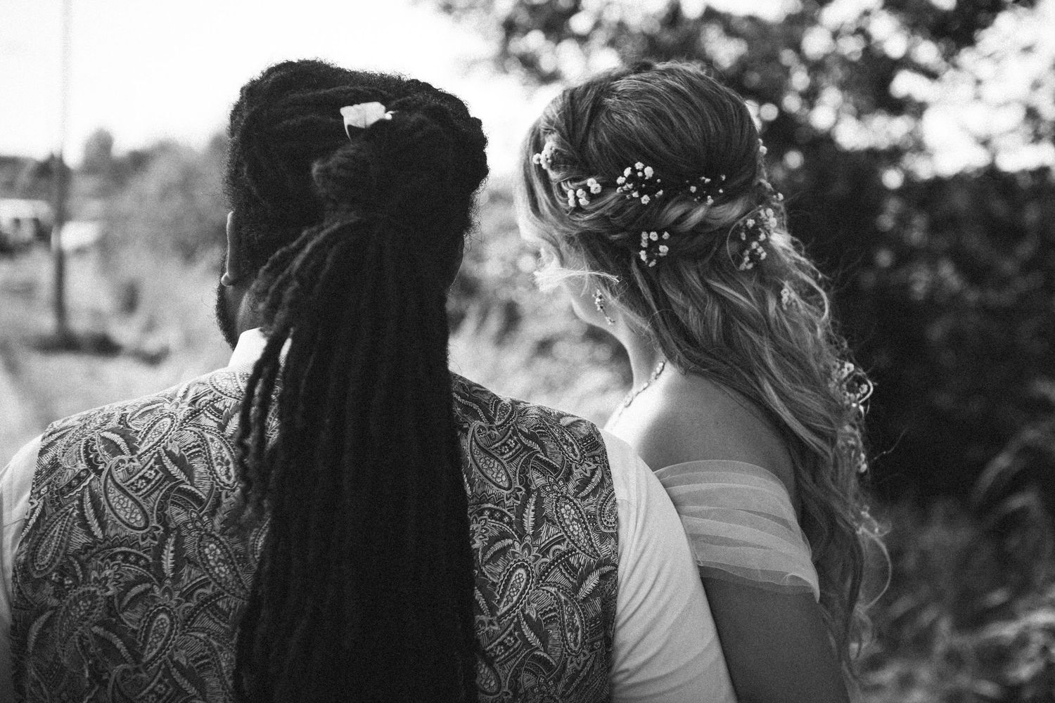 Black and white back view of bride and groom with unique hairstyles.