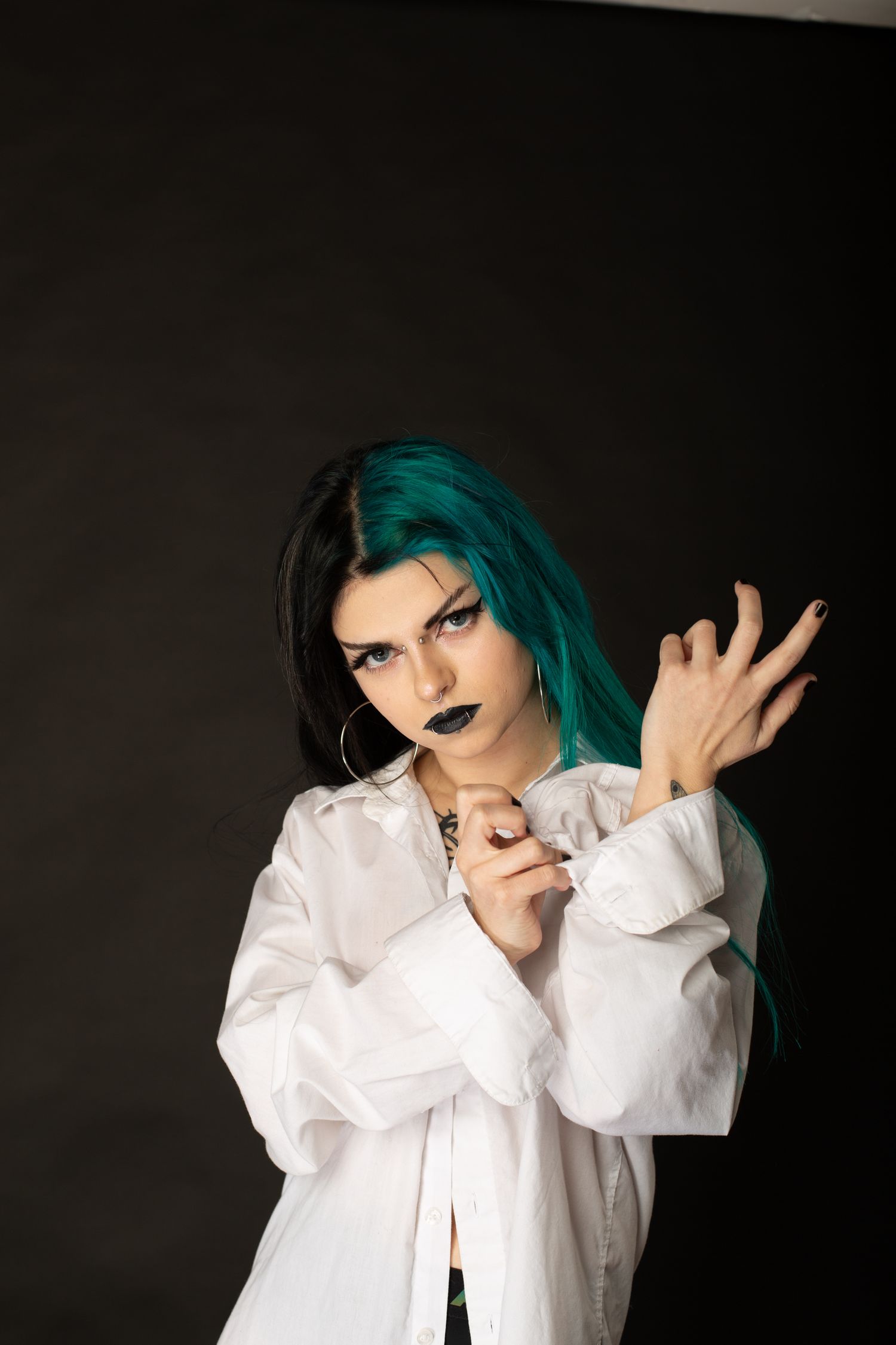 Portrait featuring two-toned hair and white button-up shirt against dark background.