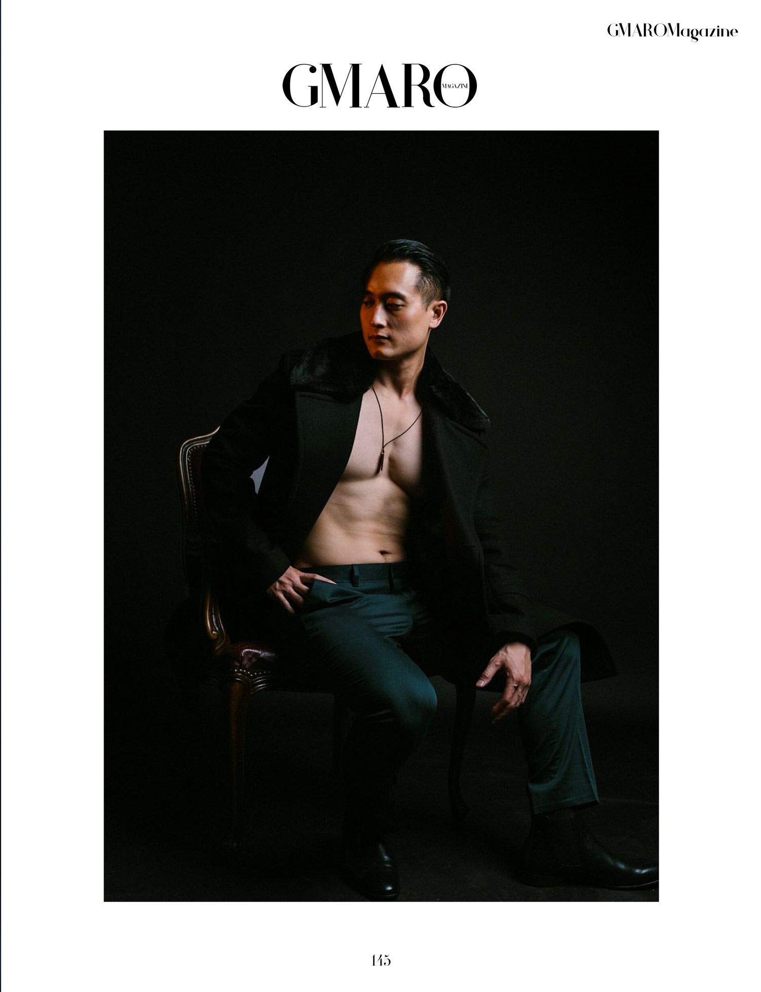 Dramatic fashion photo of model in open black coat against dark background for GMARO magazine.