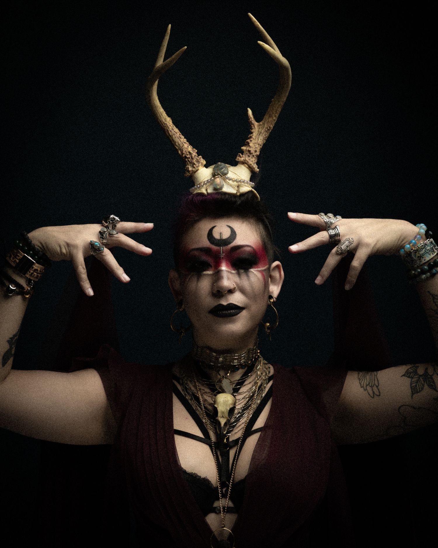 Dramatic portrait with antlers and gothic styling in dark atmospheric lighting.