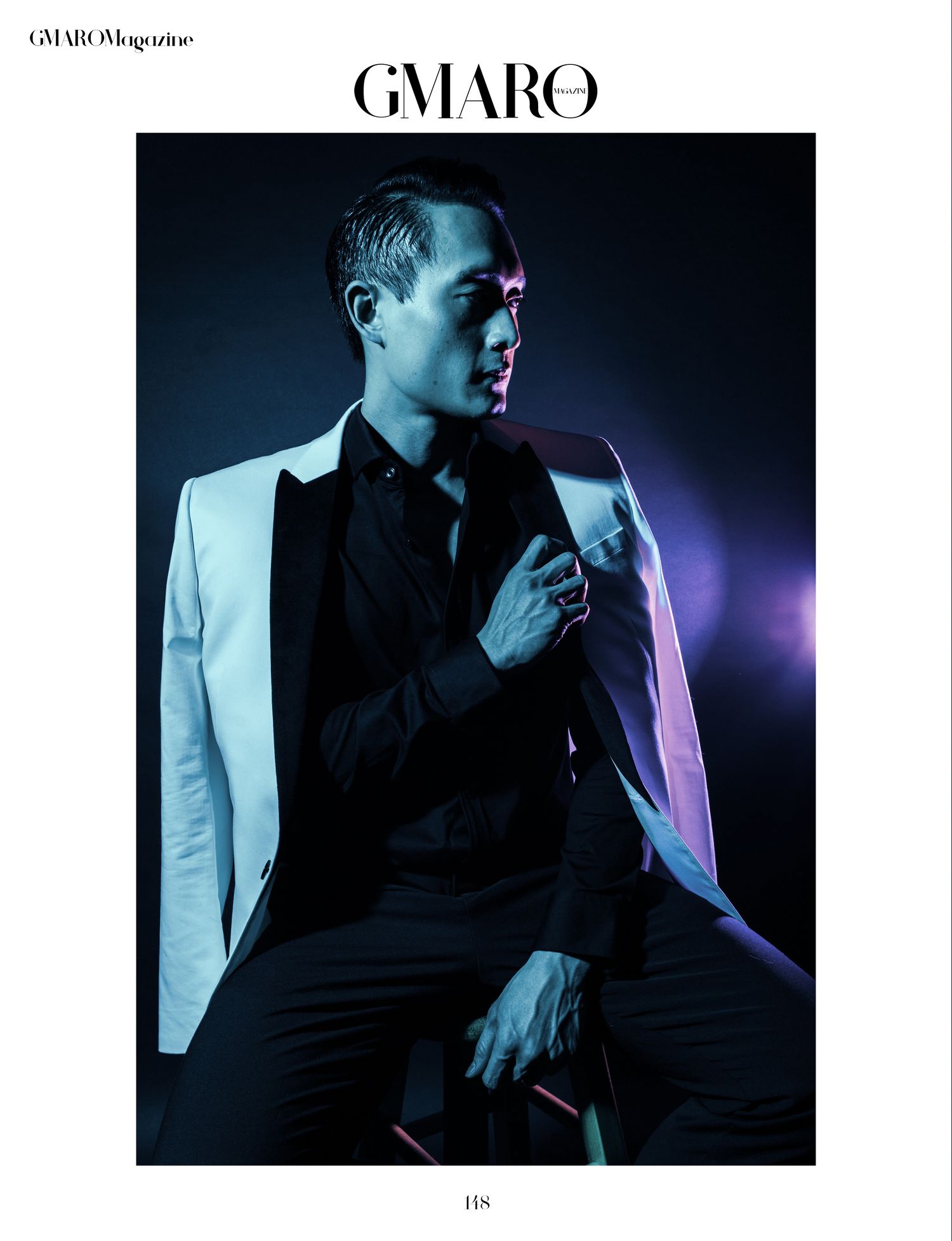 Fashion editorial shot featuring white tuxedo jacket against dramatic blue lighting.