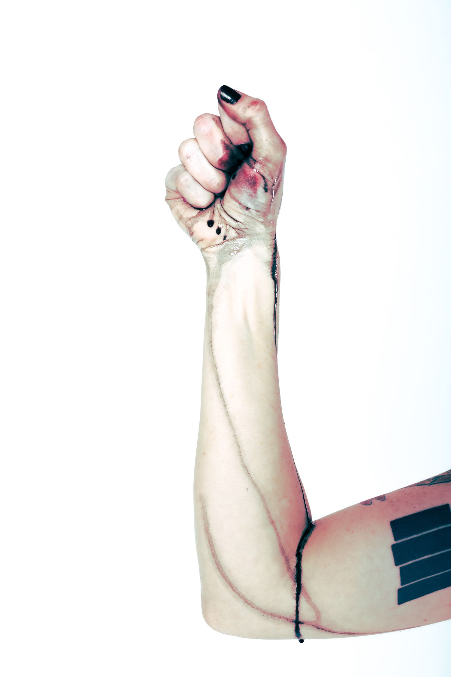 Artistic photo of raised arm with black nail polish against white background.