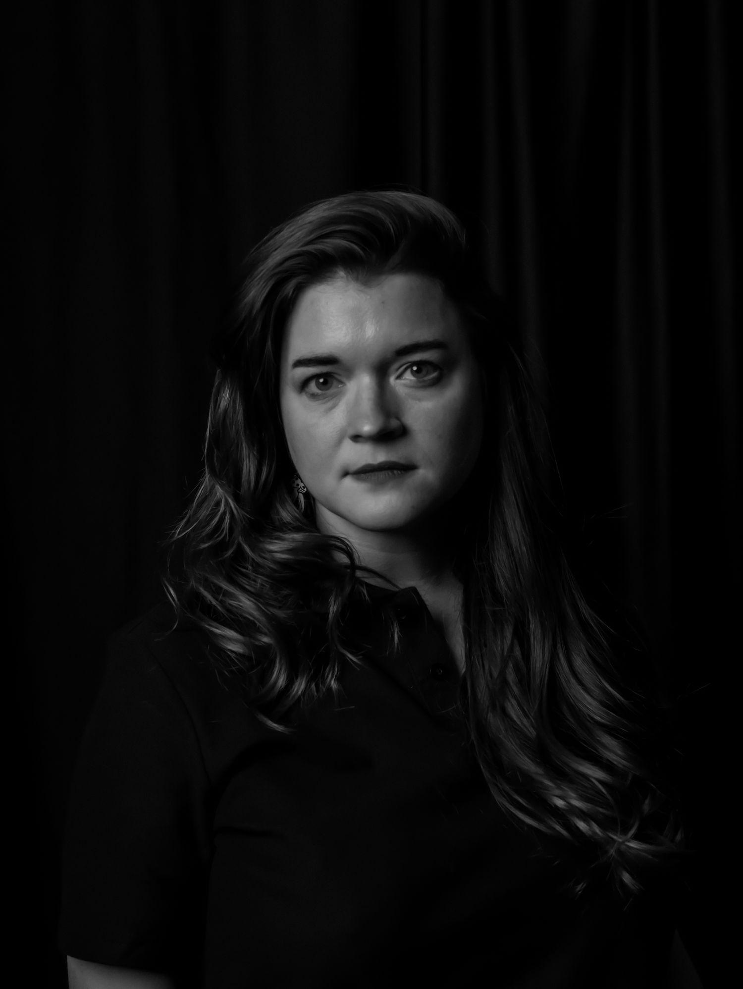Classic black and white portrait with dramatic lighting against dark backdrop.